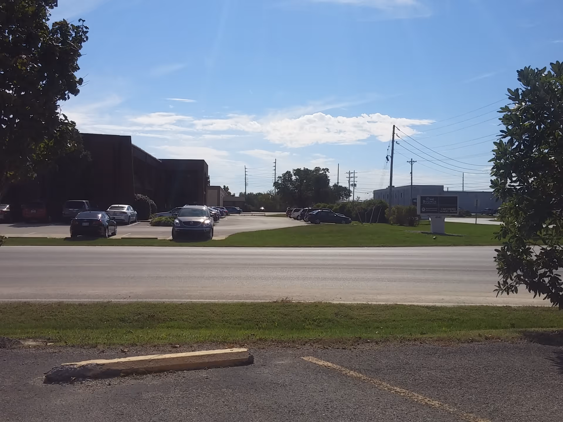 Exterior view of Caretenders facility with parking lot, road, and trees.