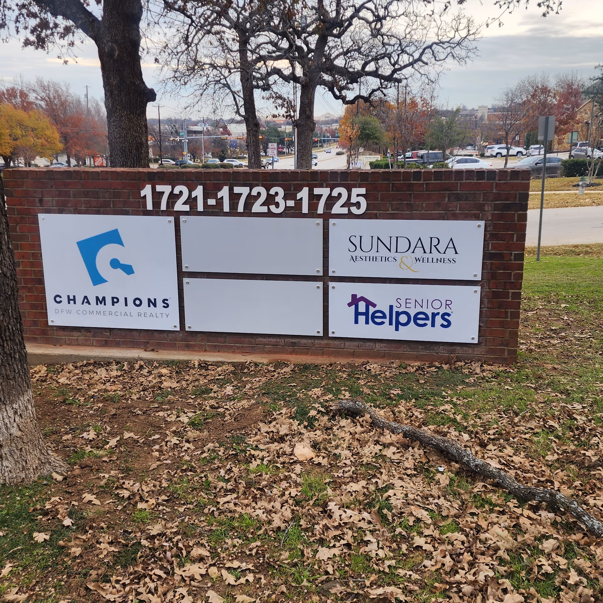 Brick sign display with large numbers and logos for Champions, Sundara, and Senior Helpers outdoors.