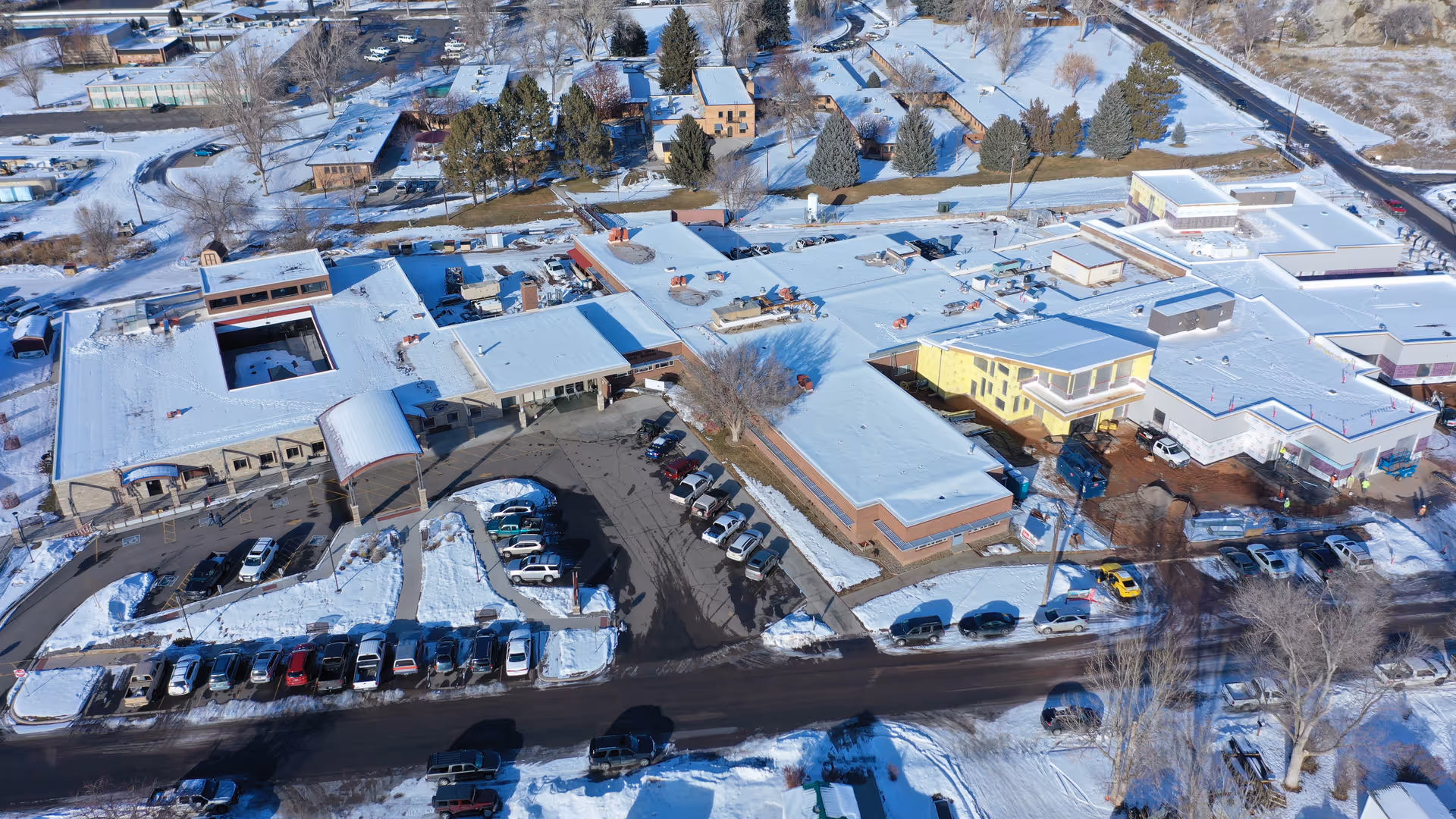 Aerial view of a snow-covered senior living campus with multiple connected buildings and parking.