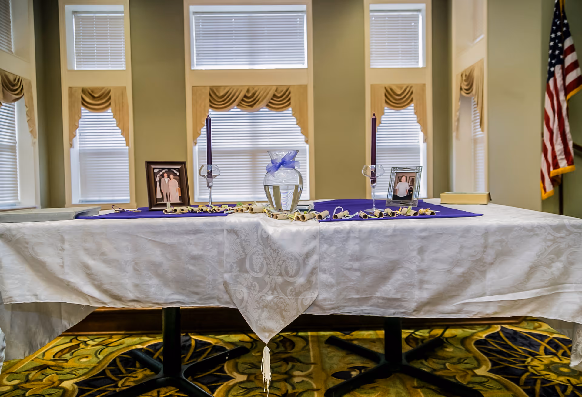 Memorial display table with photos and candles in an interior room.