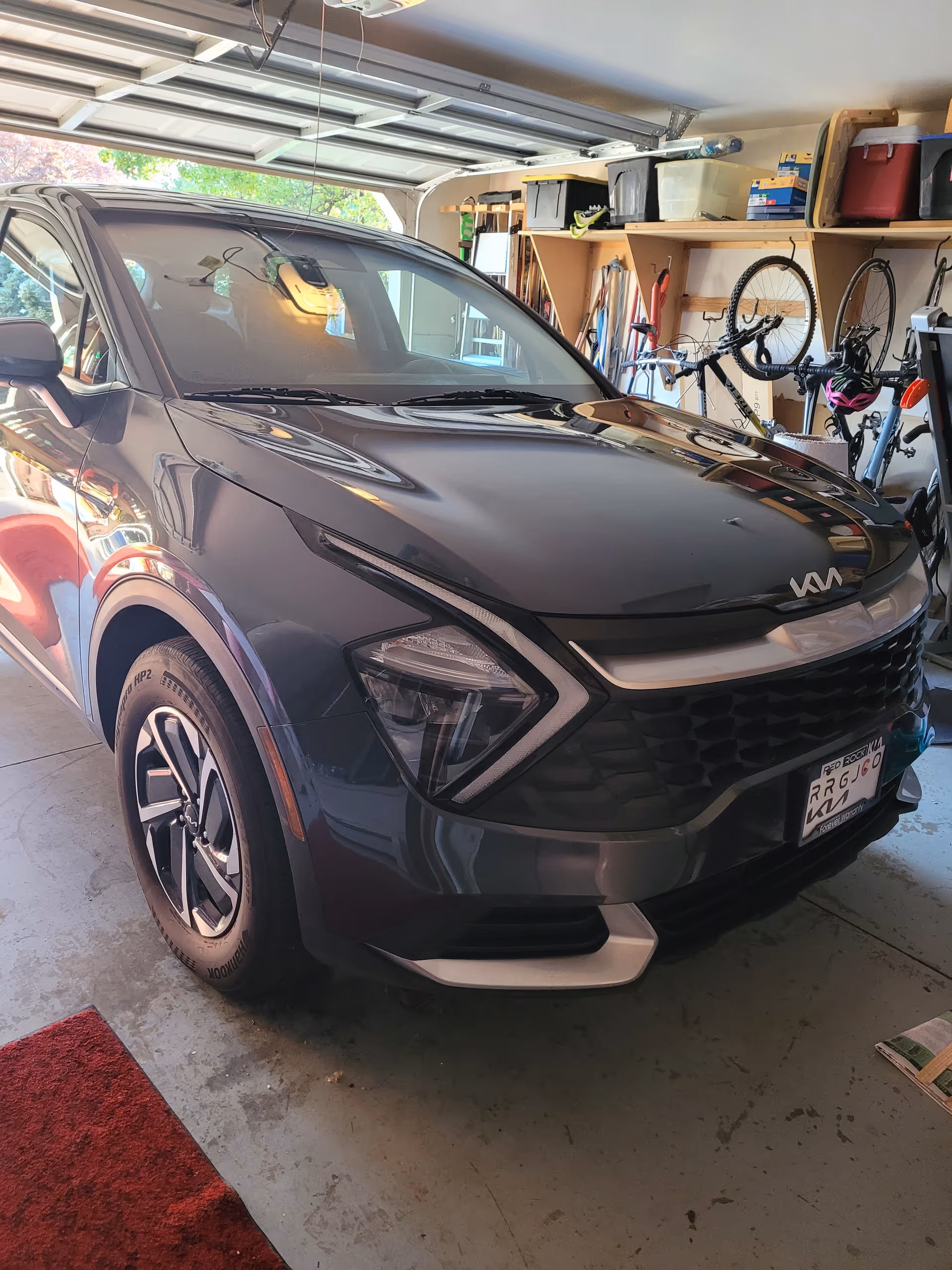 Dark gray SUV parked inside a garage with bikes and storage shelves.