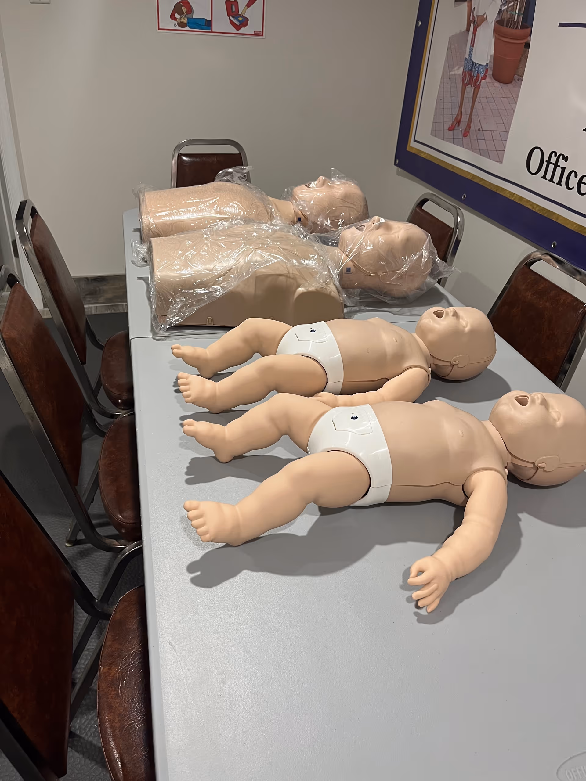 Infant care mannequins and training dummies on a classroom table.