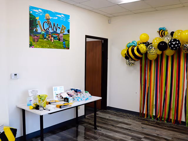 A small indoor room with a table of supplies and colorful balloon decorations.