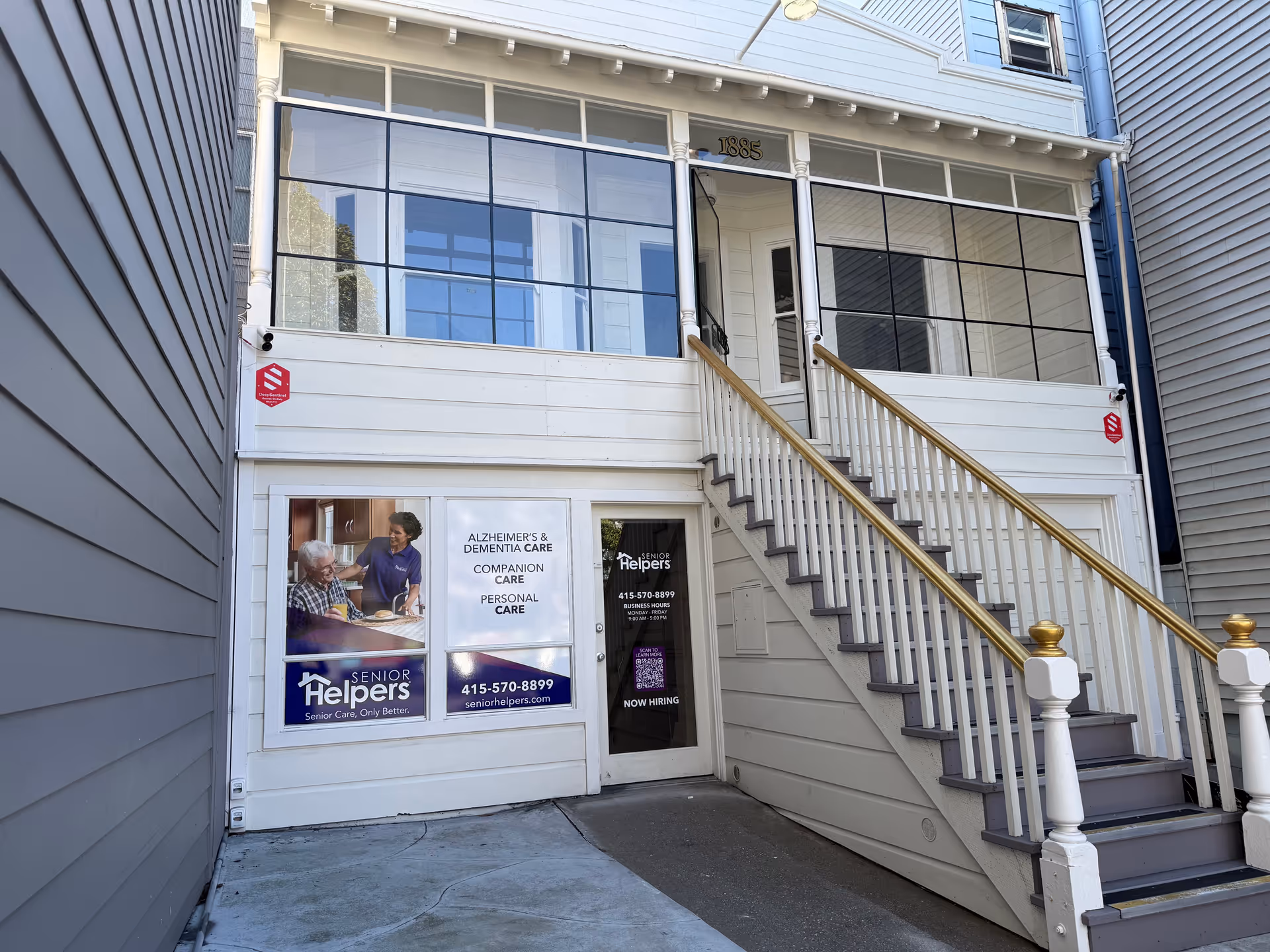Two-story building facade with staircase, glass storefront, and Senior Helpers posters.
