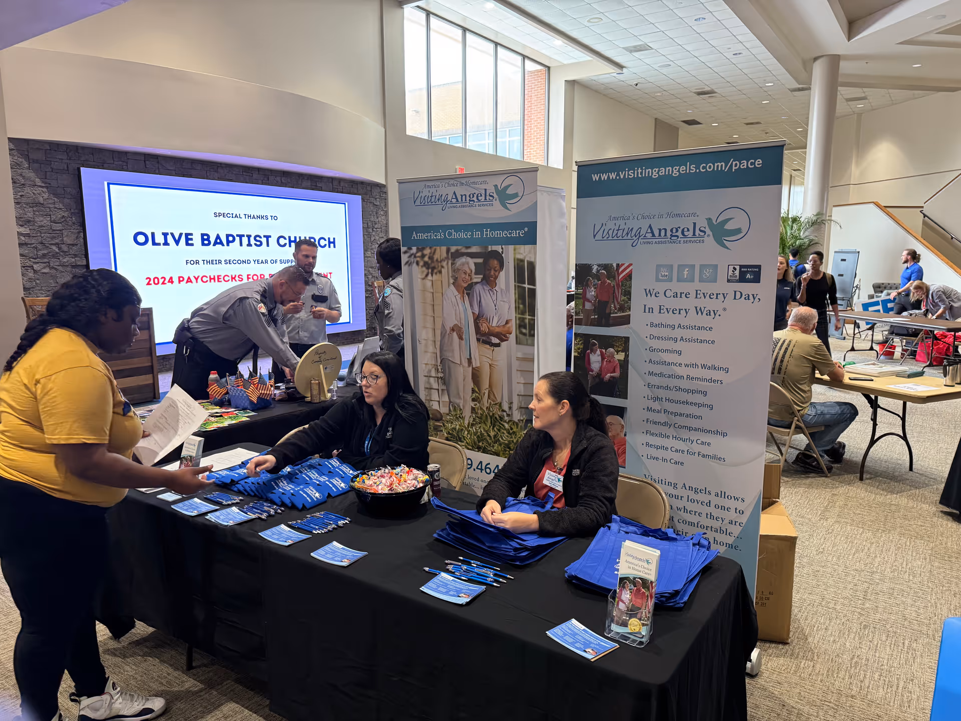 Indoor expo booth for Visiting Angels with staff, banners, and tables of information.