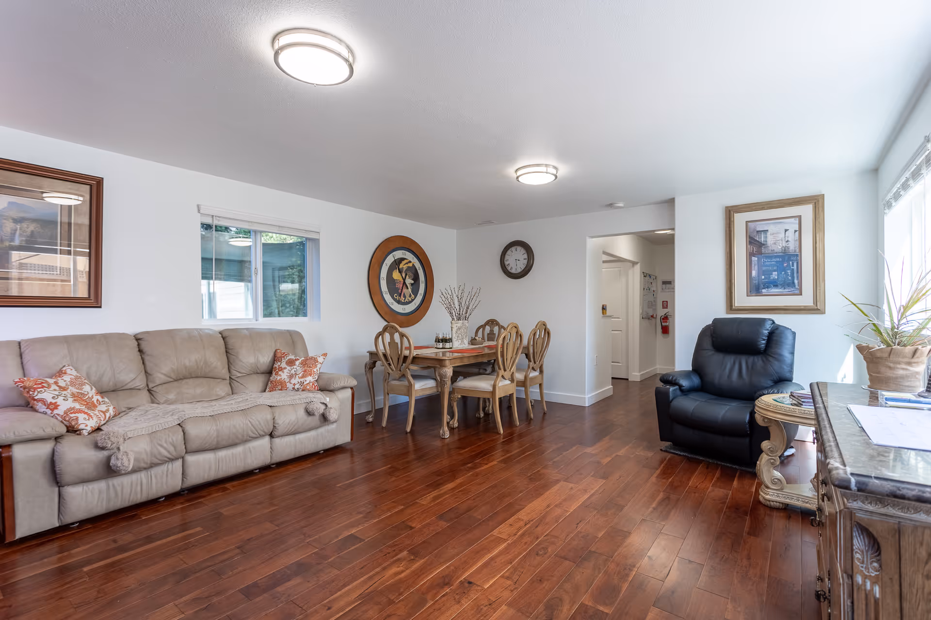 Spacious living room with beige sofa, dining table, chairs, and a black recliner.