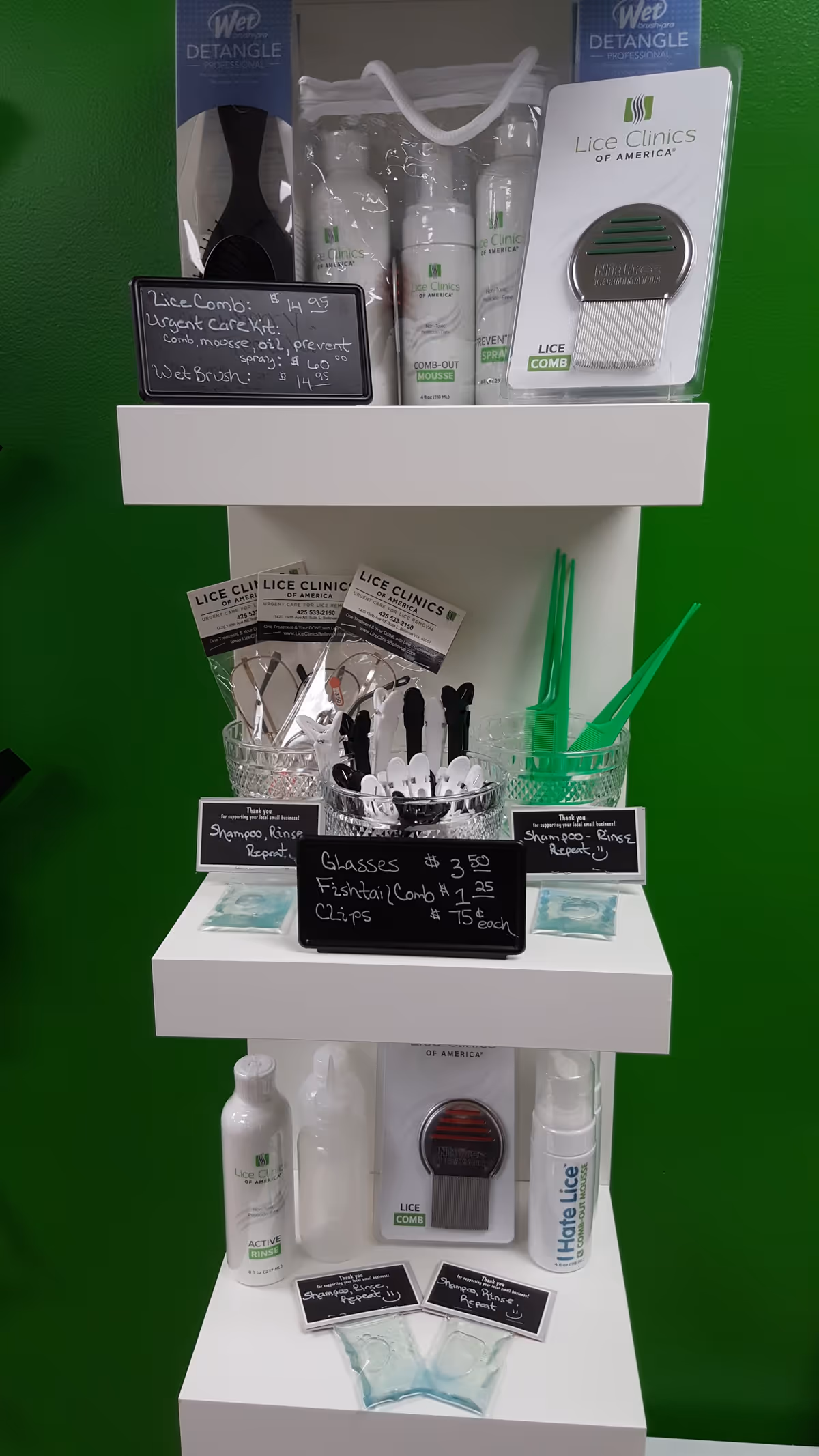 A white display shelf features Lice Clinics of America products on a bright green wall.
