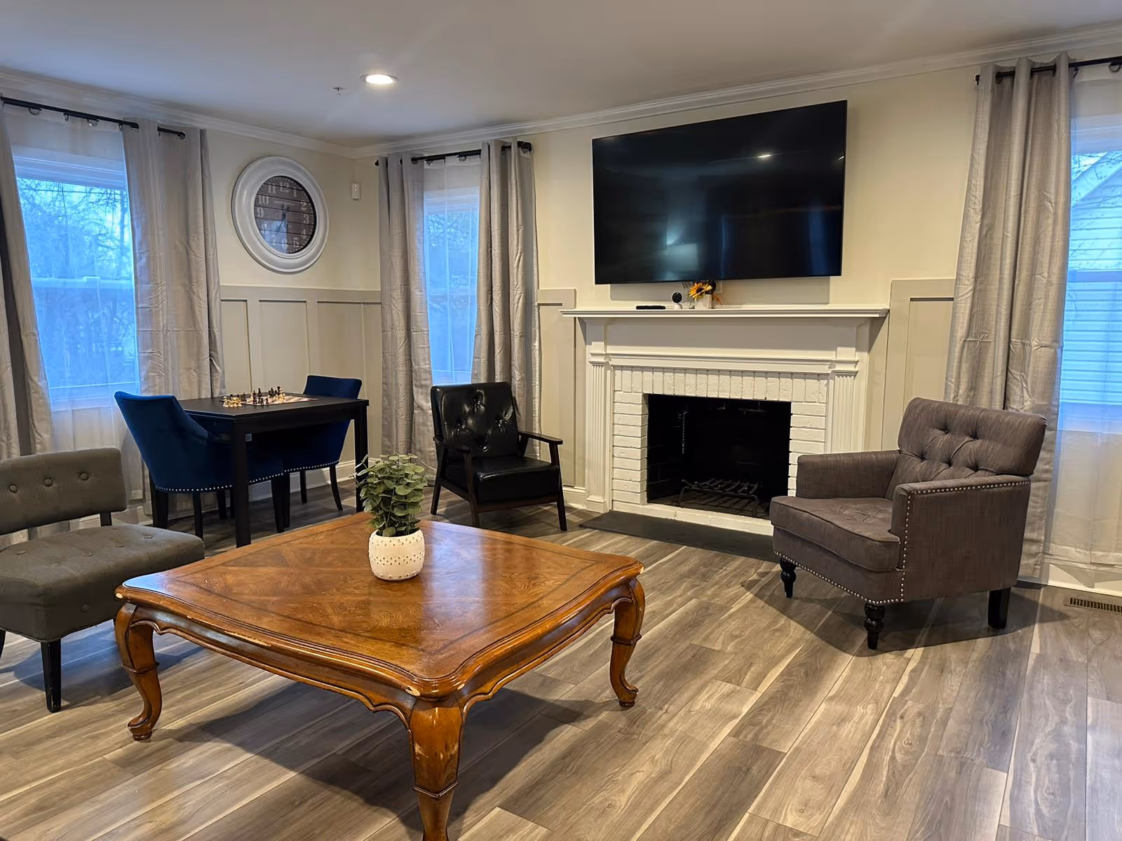 Cozy living room with fireplace, mounted TV, cushioned chairs, and a wooden coffee table.