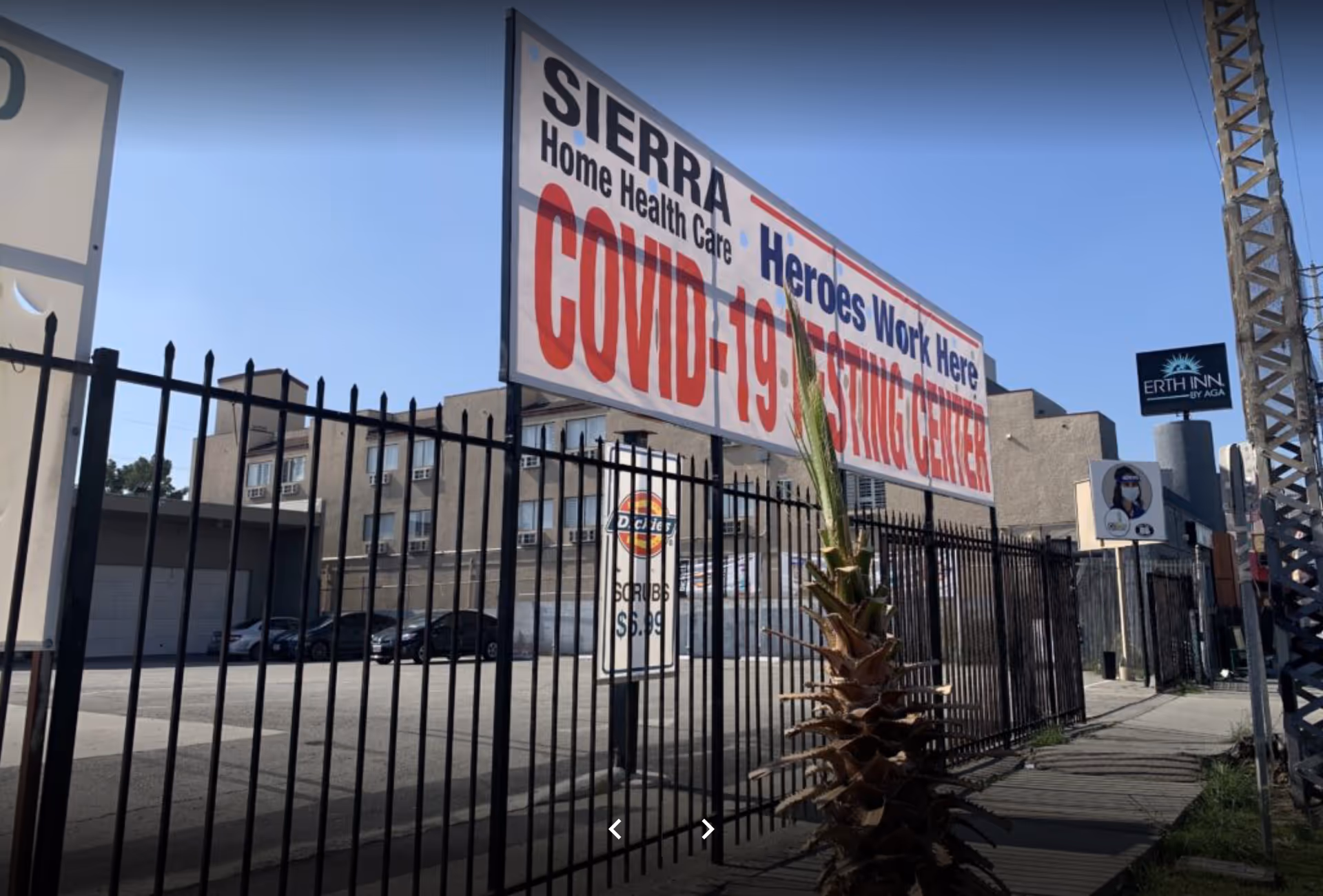 A large Sierra Healthcare Partners COVID-19 testing center sign beside a fenced street.