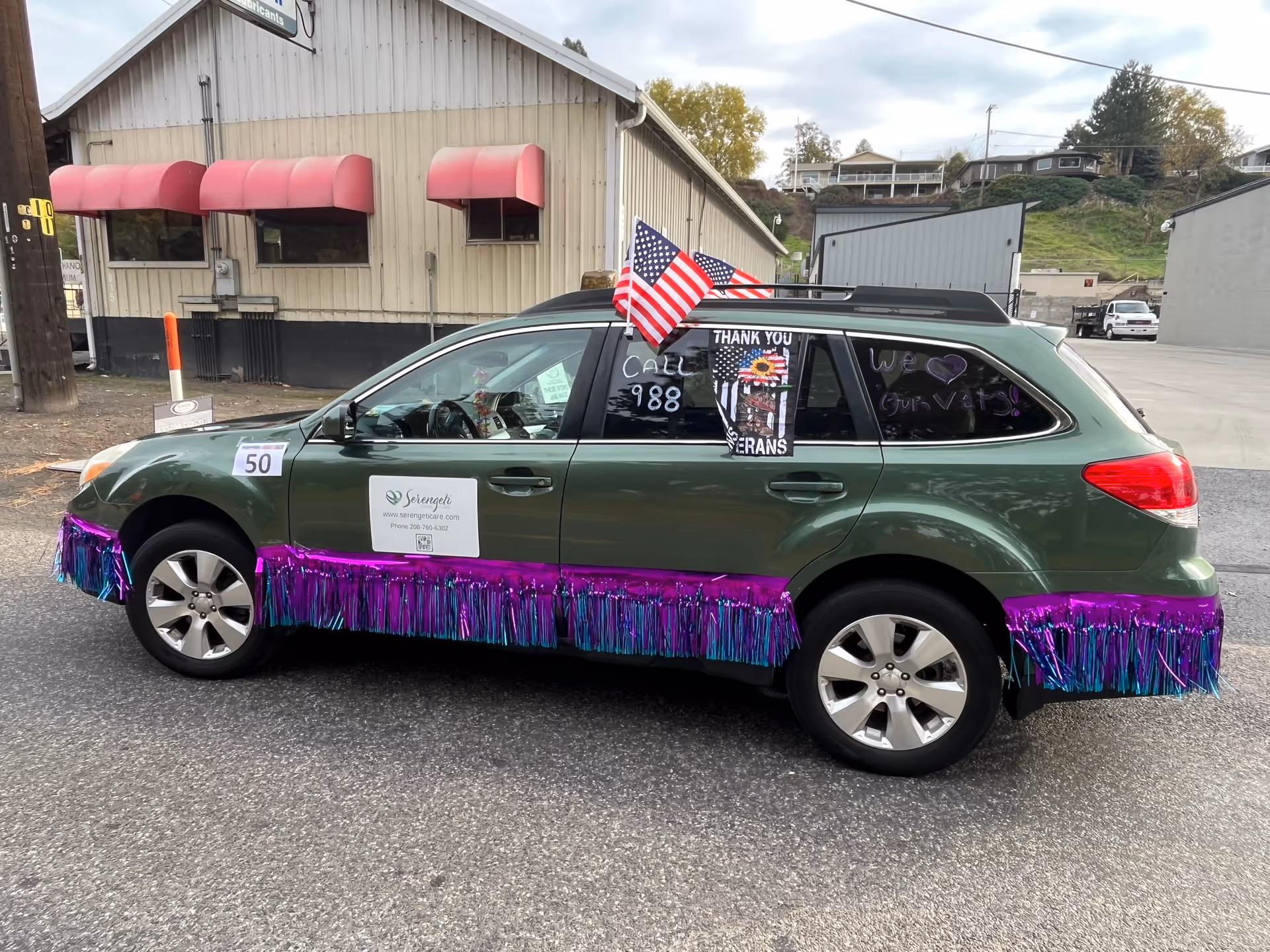 A green SUV decorated with purple fringe and an American flag parked outside Serengeti Care.