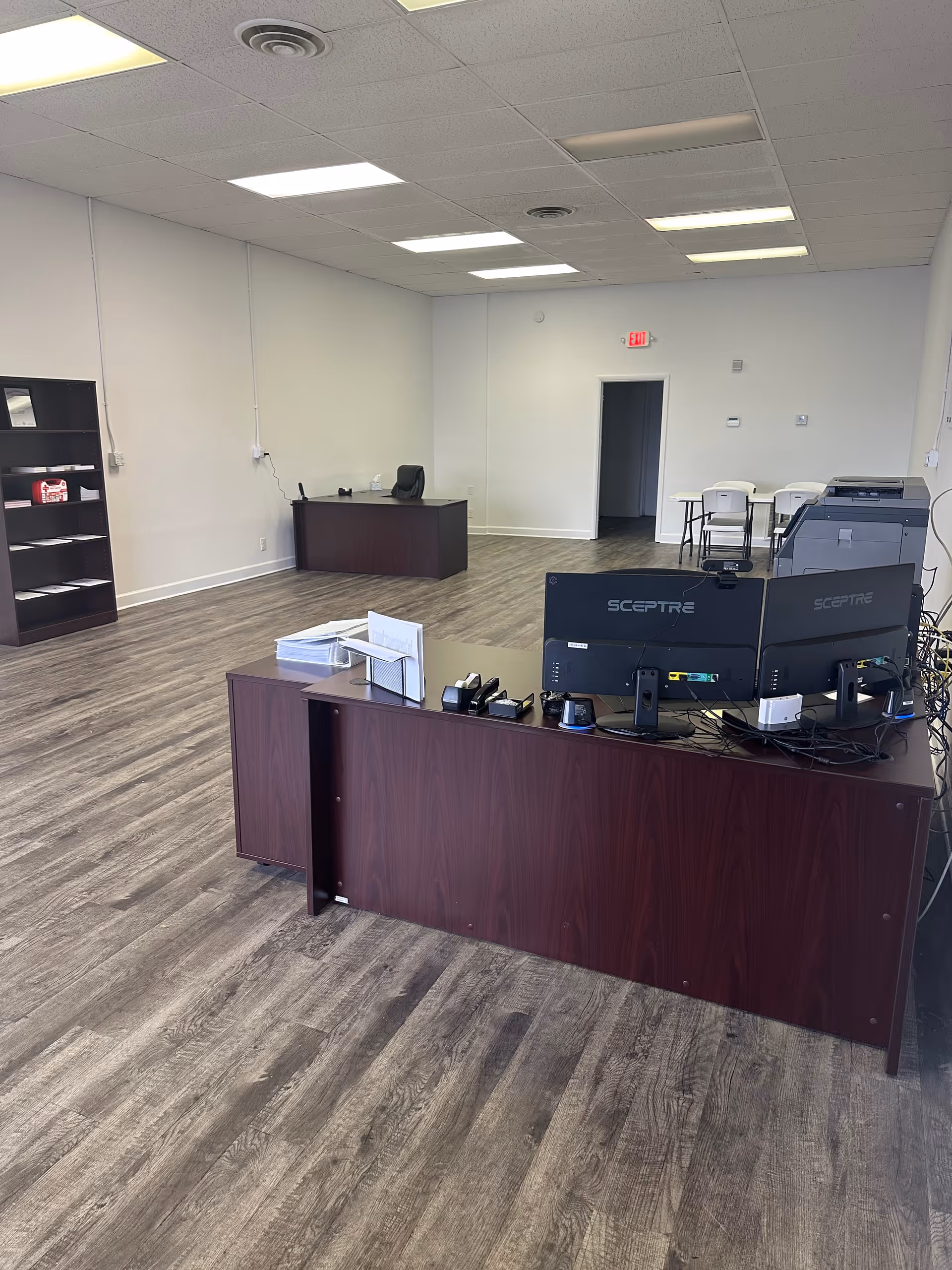 Reception desk with dual computer monitors in a spacious, empty office area.