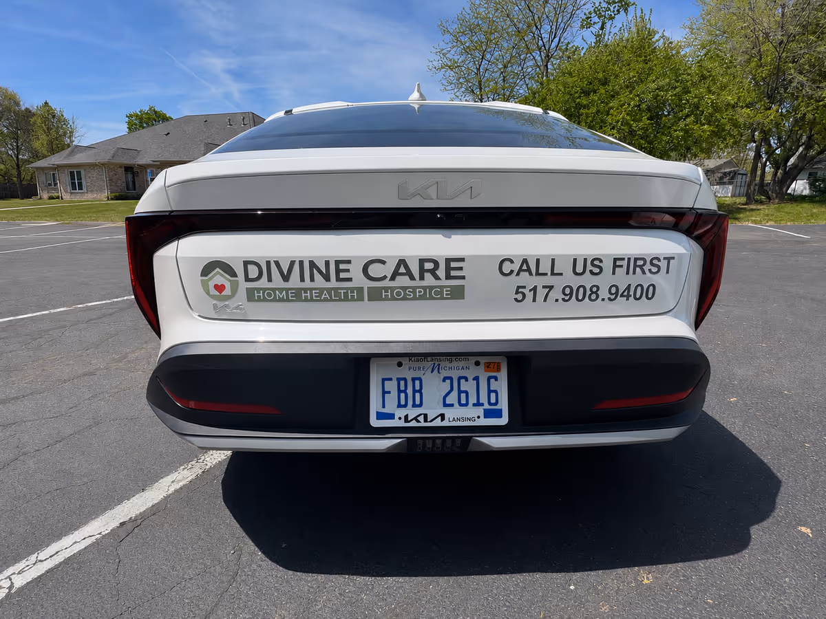 Rear view of a vehicle advertising Divine Care Home Health and Hospice in a parking lot.