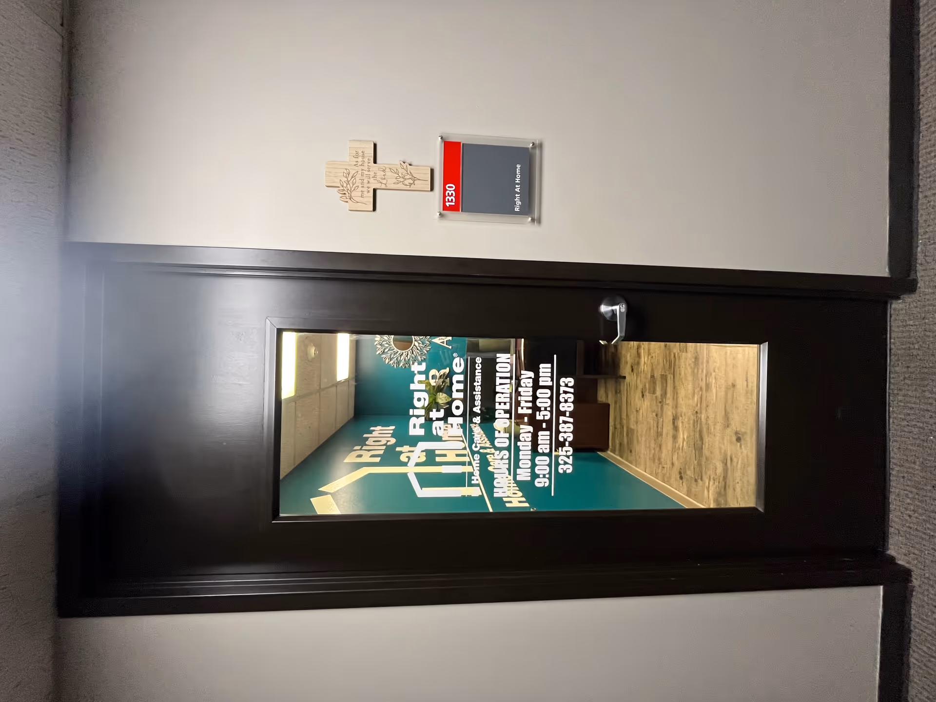 Dark-framed interior door with a window displaying teal signage for Right at Home.