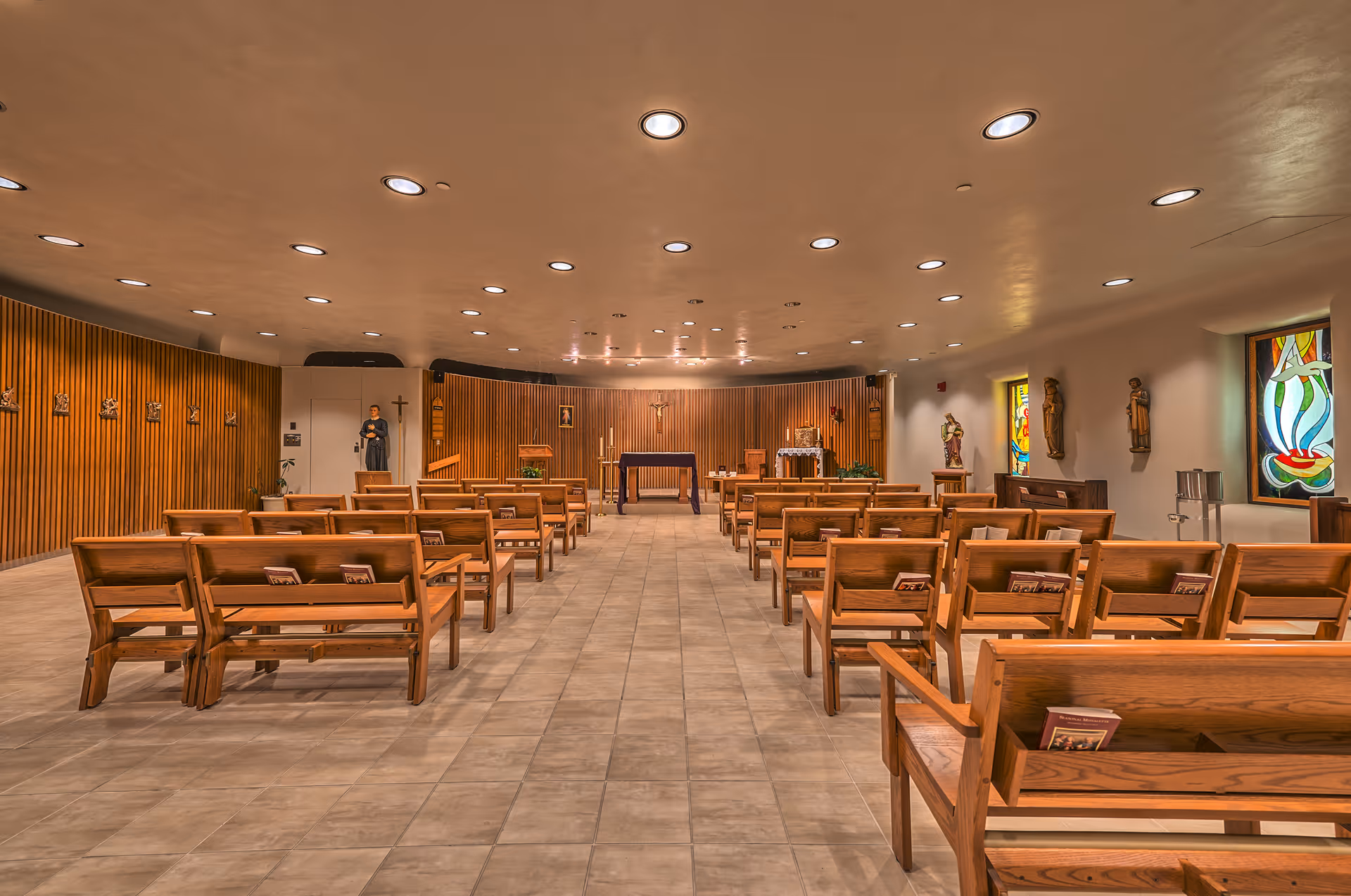 Inside a senior facility chapel with wooden pews, stained glass windows, and an altar.