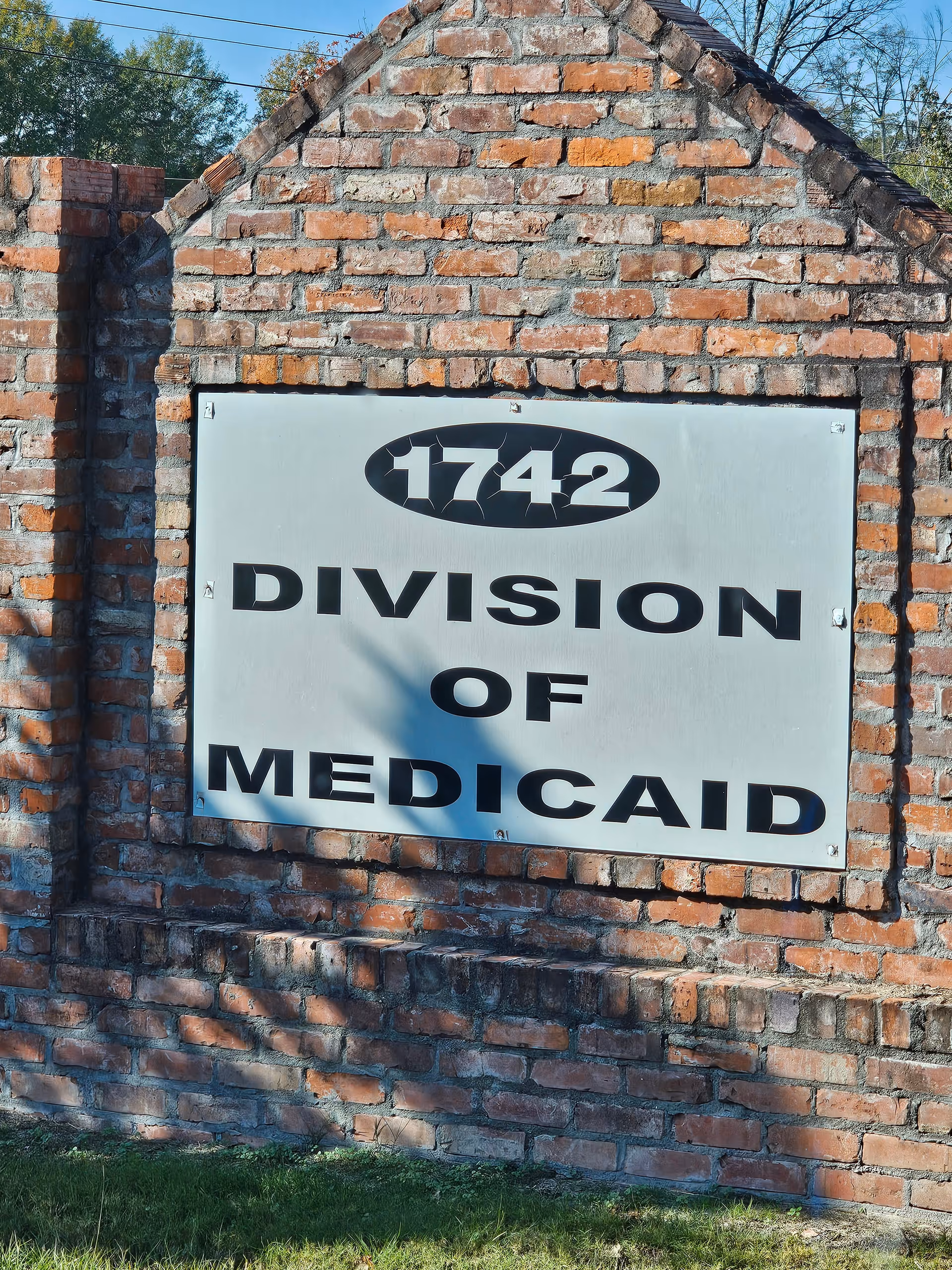 Brick wall with a large metal sign reading 1742 Division of Medicaid.