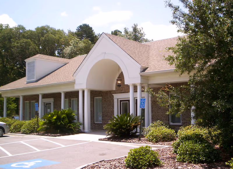Compassus senior living facility exterior featuring brick walls and an arched entrance.