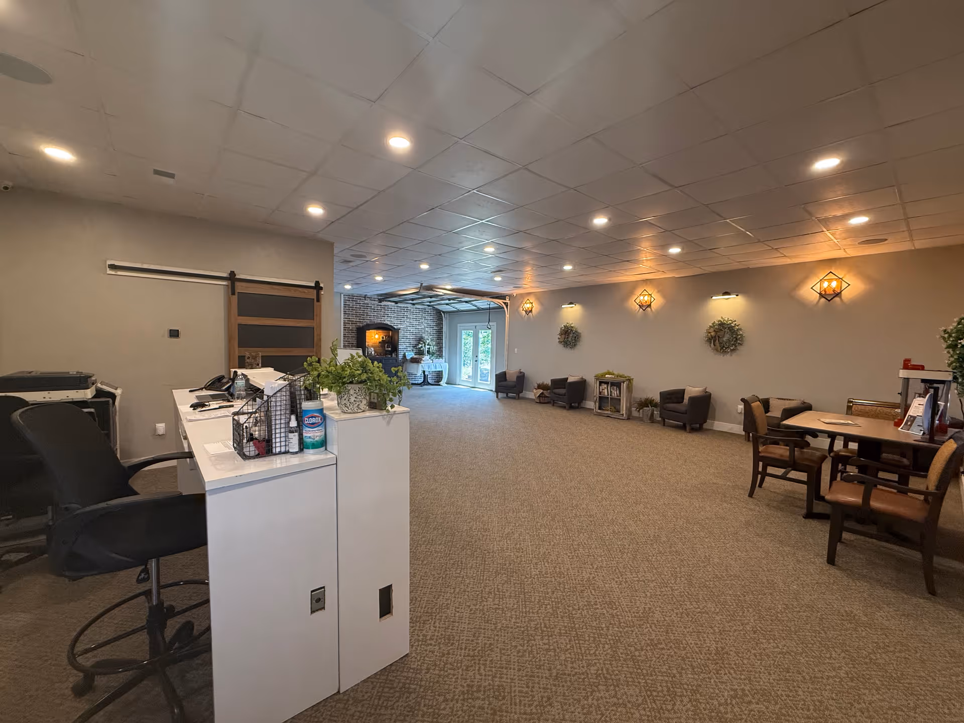 Bright interior lobby with a reception desk, chairs, tables, and wall sconces.