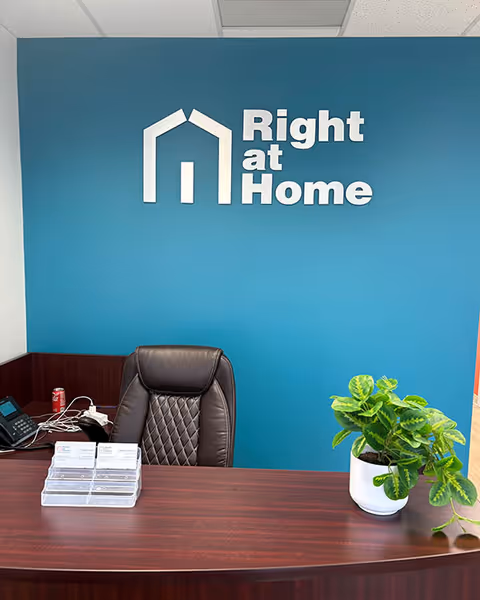Reception desk sits against a teal wall with a prominent Right at Home logo.