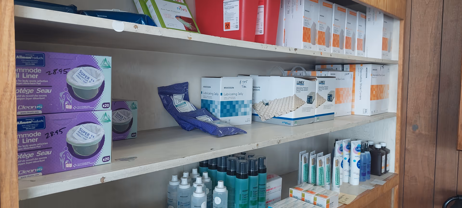 Shelves stocked with medical supplies and boxes inside a wooden cabinet.