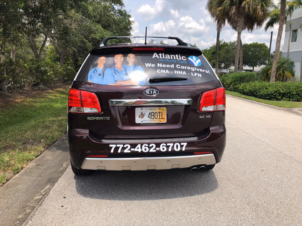 Rear of a maroon Kia Sorento displaying Atlantic In-Home Care advertisement on the rear window.