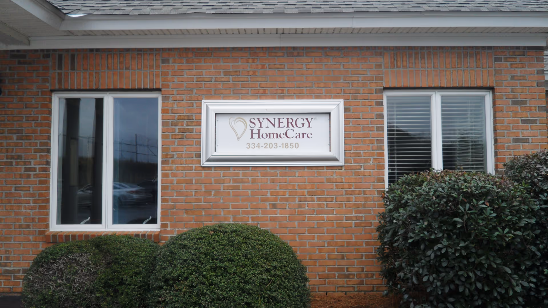 Brick building exterior featuring a Synergy HomeCare sign between two windows.