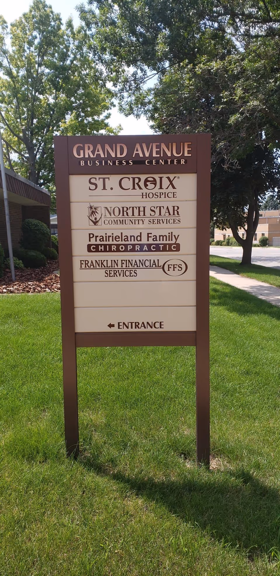 Outdoor signboard on a grassy lawn listing multiple businesses, including St. Croix Hospice.