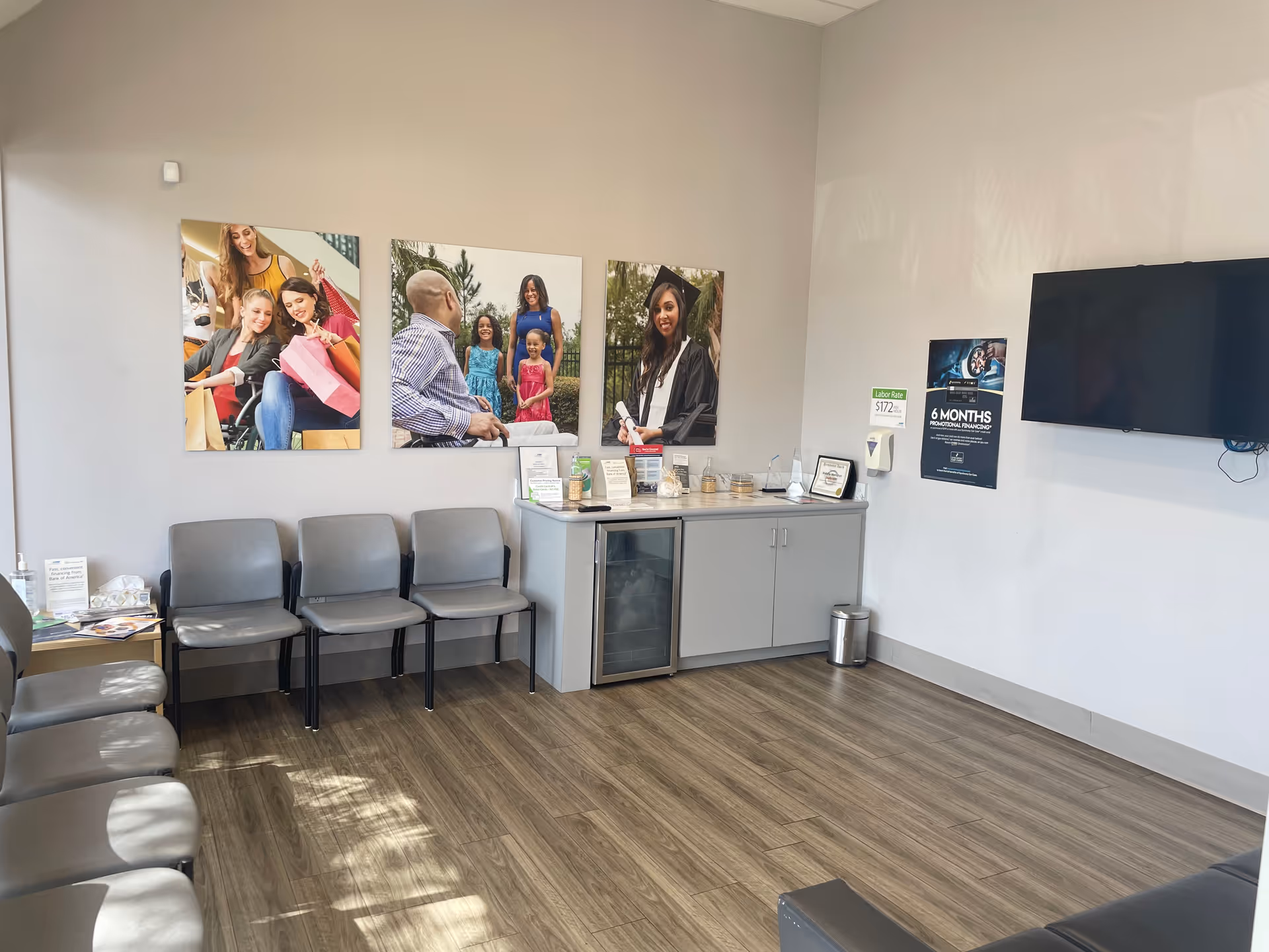 A waiting area with gray chairs, a counter, wall art, and a wall-mounted TV.