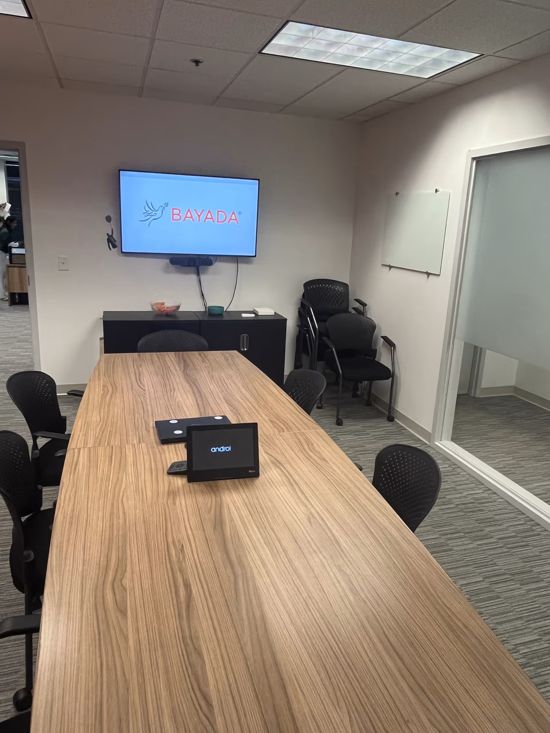 A long conference table in a meeting room with a BAYADA screen on the wall.
