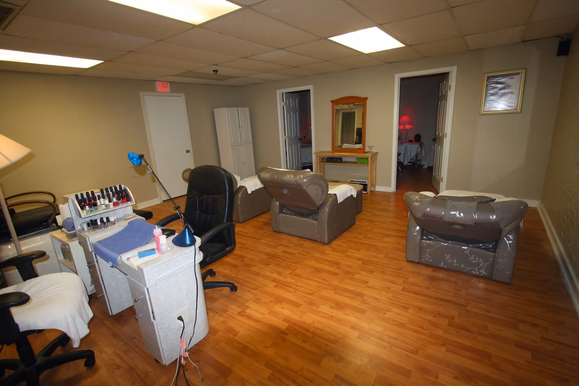 Nail salon area with polish display, manicure station, and multiple chairs inside a spacious room.