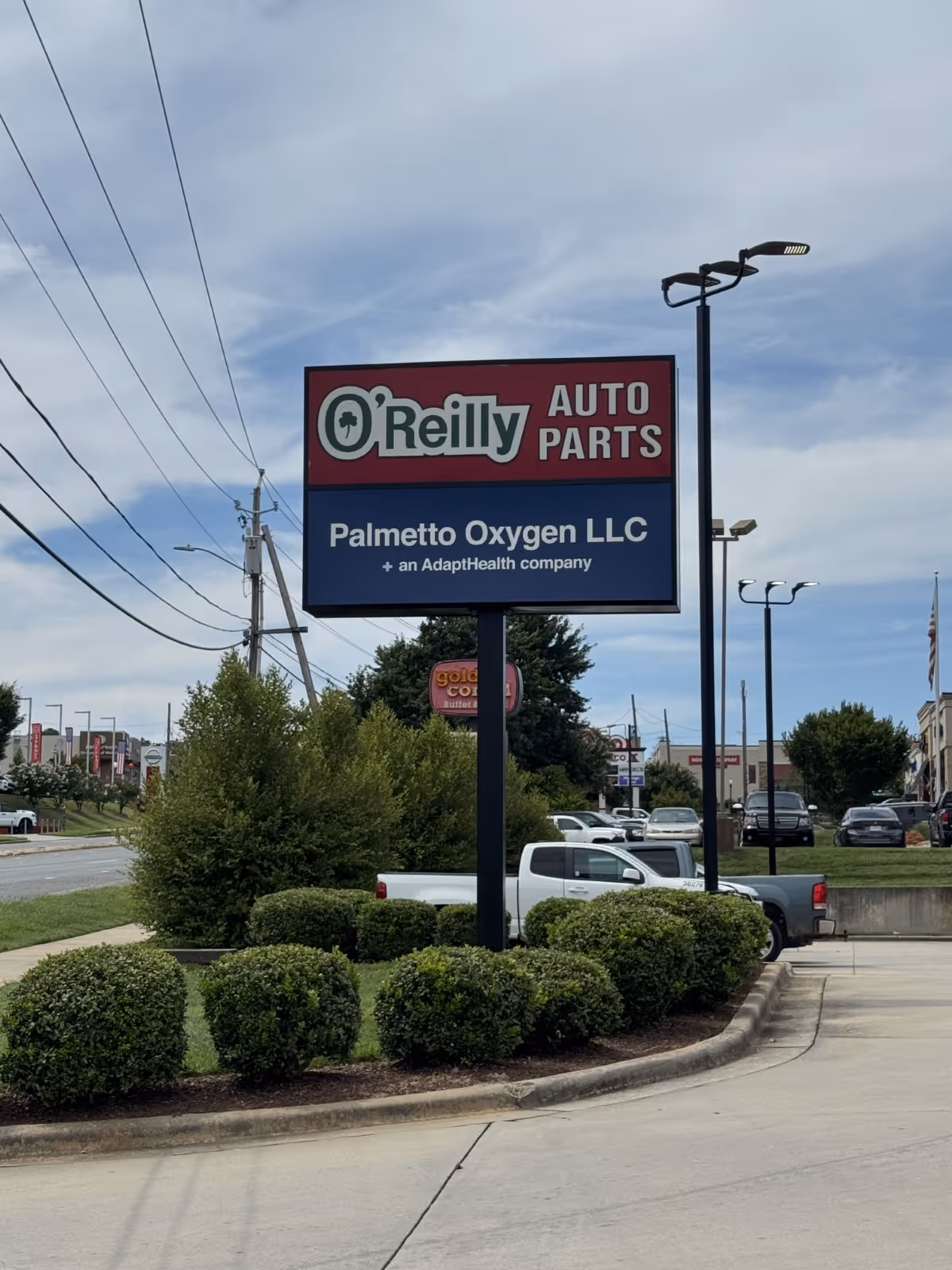 O'Reilly Auto Parts sign with Palmetto Oxygen LLC branding beside trimmed shrubs.