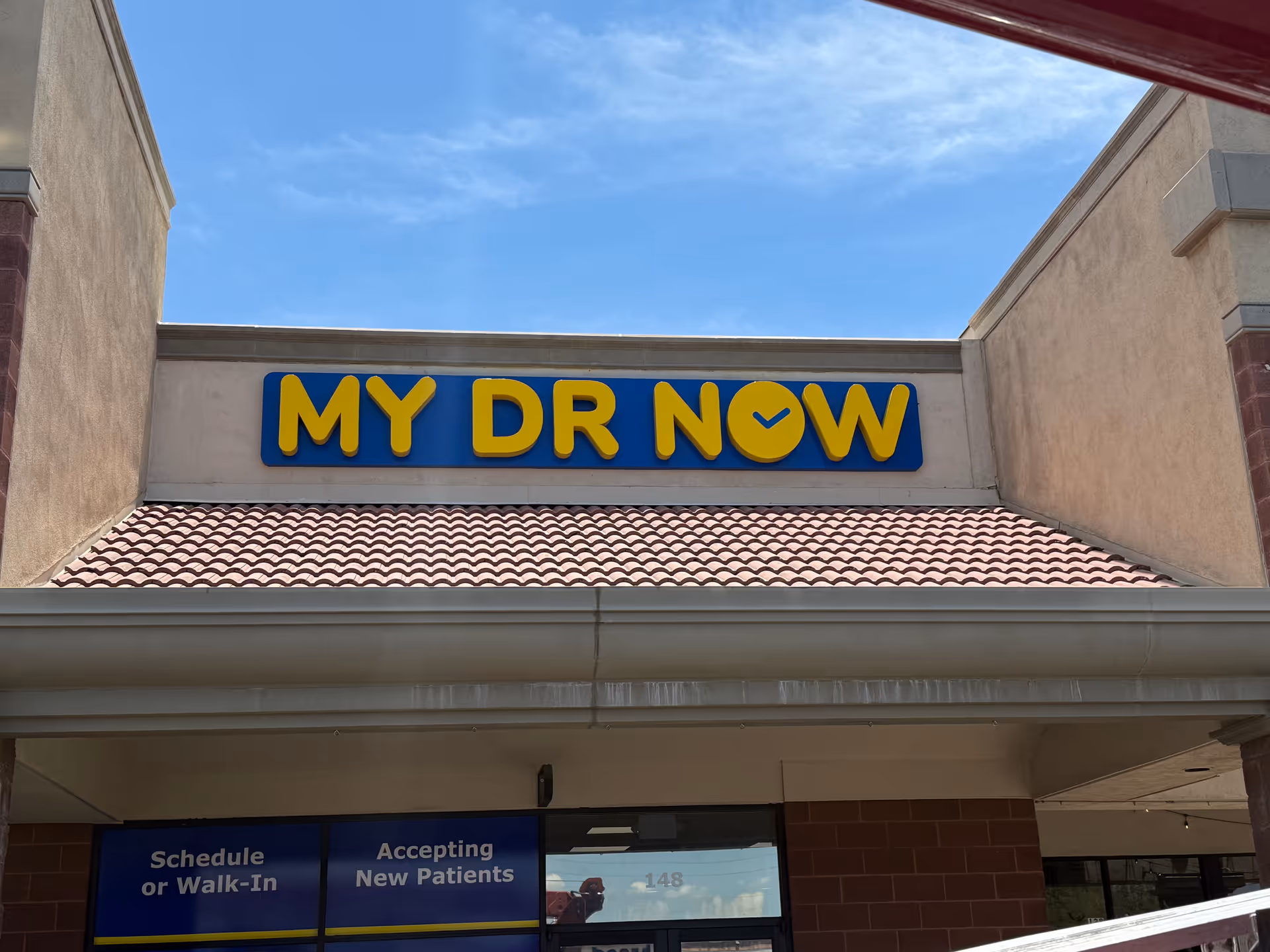 Exterior view of a strip mall-style building with a blue and yellow MY DR NOW sign.