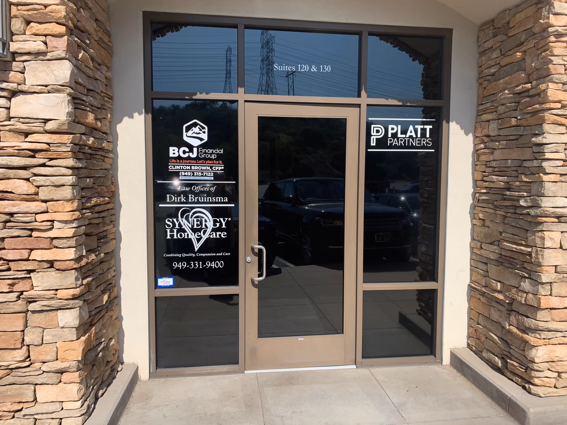 Entrance of a senior care facility with stone walls and glass doors displaying Synergy HomeCare signage.