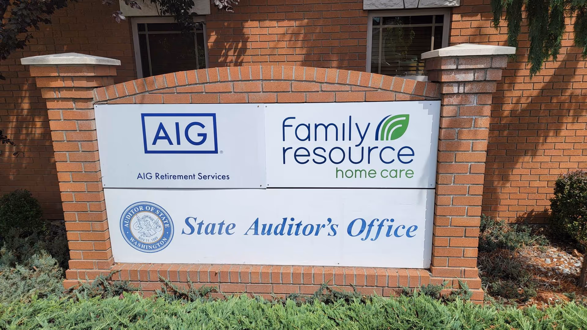 Outdoor brick sign displaying Family Resource Home Care and State Auditor's Office logos.