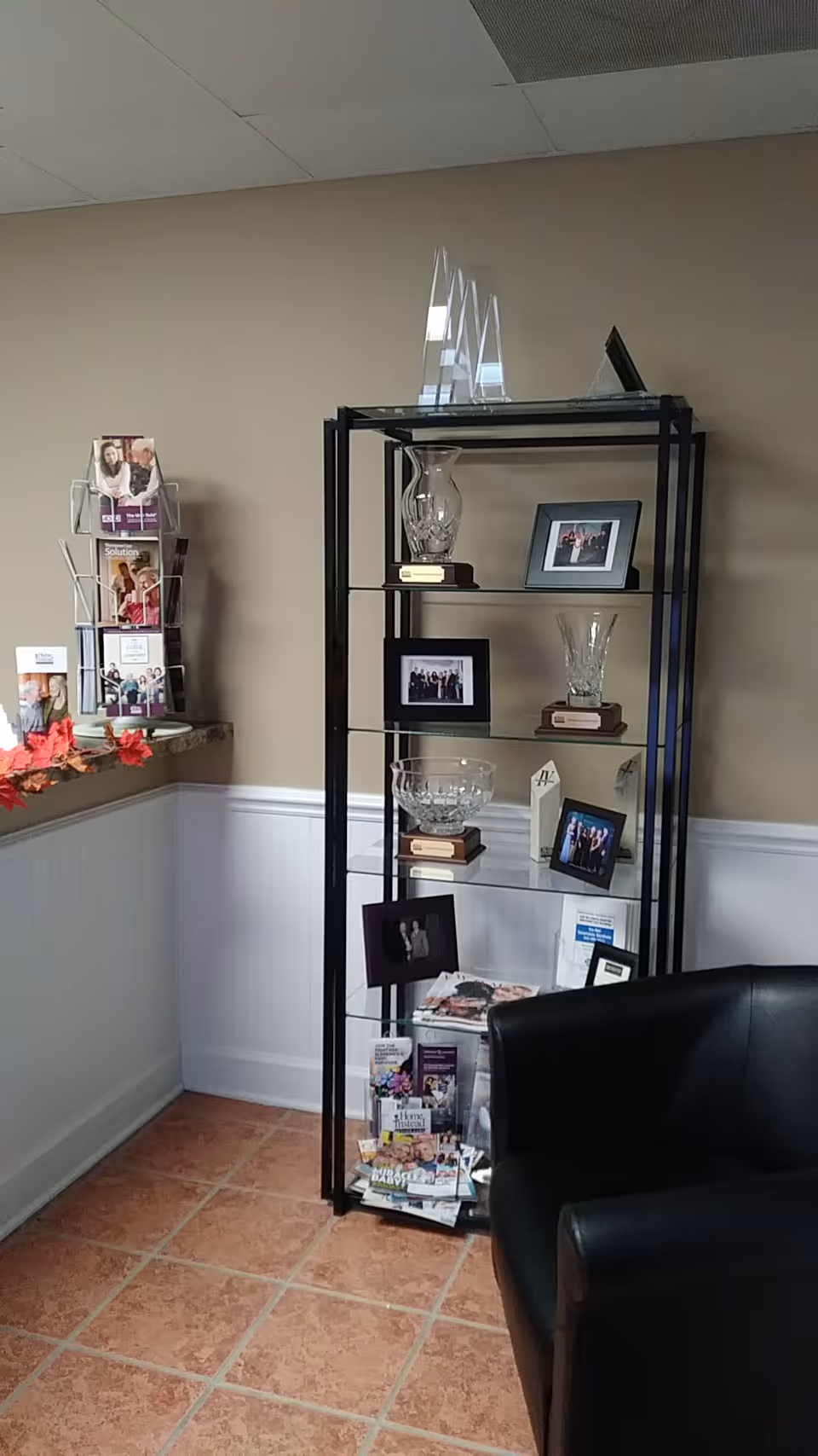 Interior lobby with a black metal display shelf holding photos and glassware.