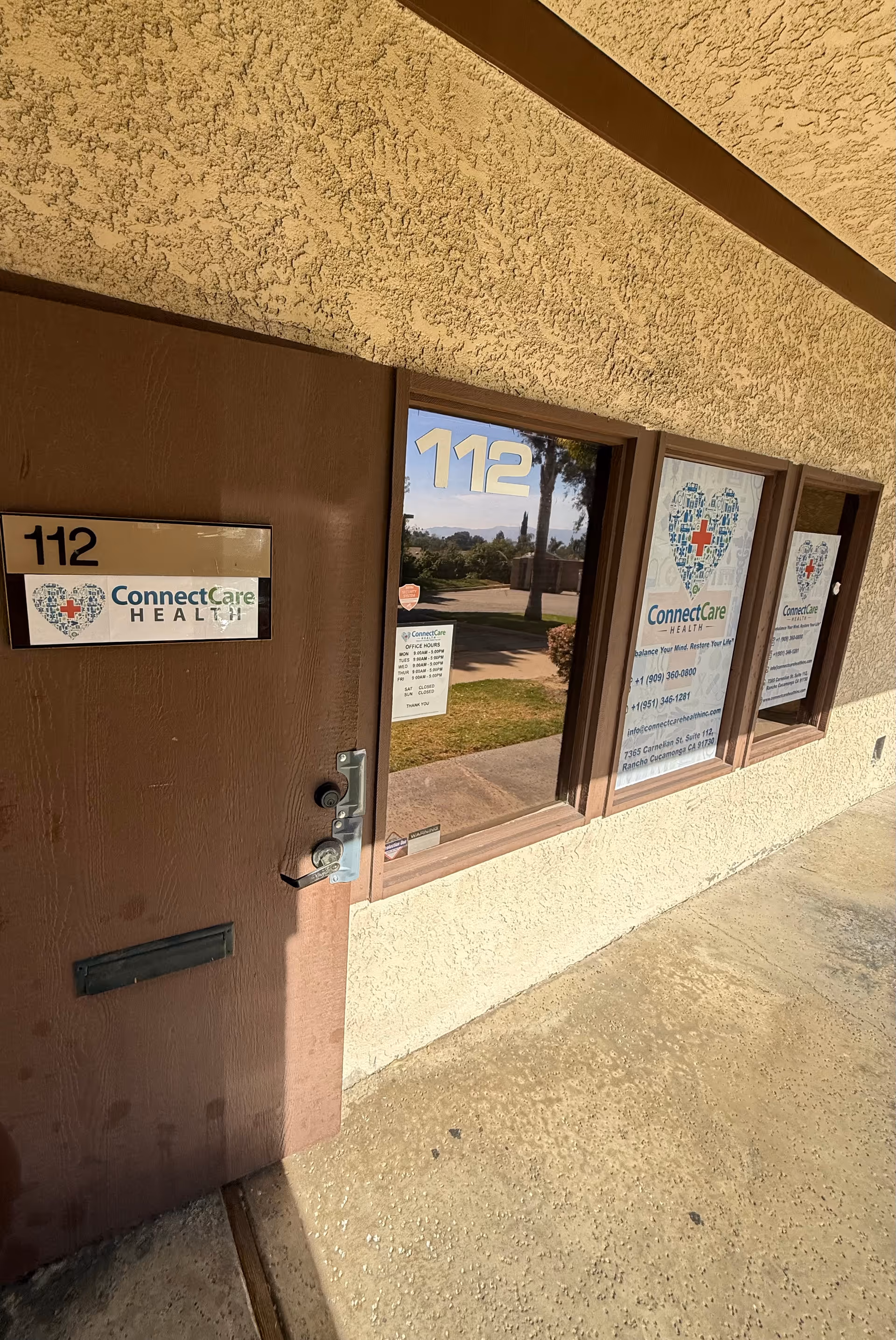 Exterior view of ConnectCare Health entrance with door, windows, and posted signs.