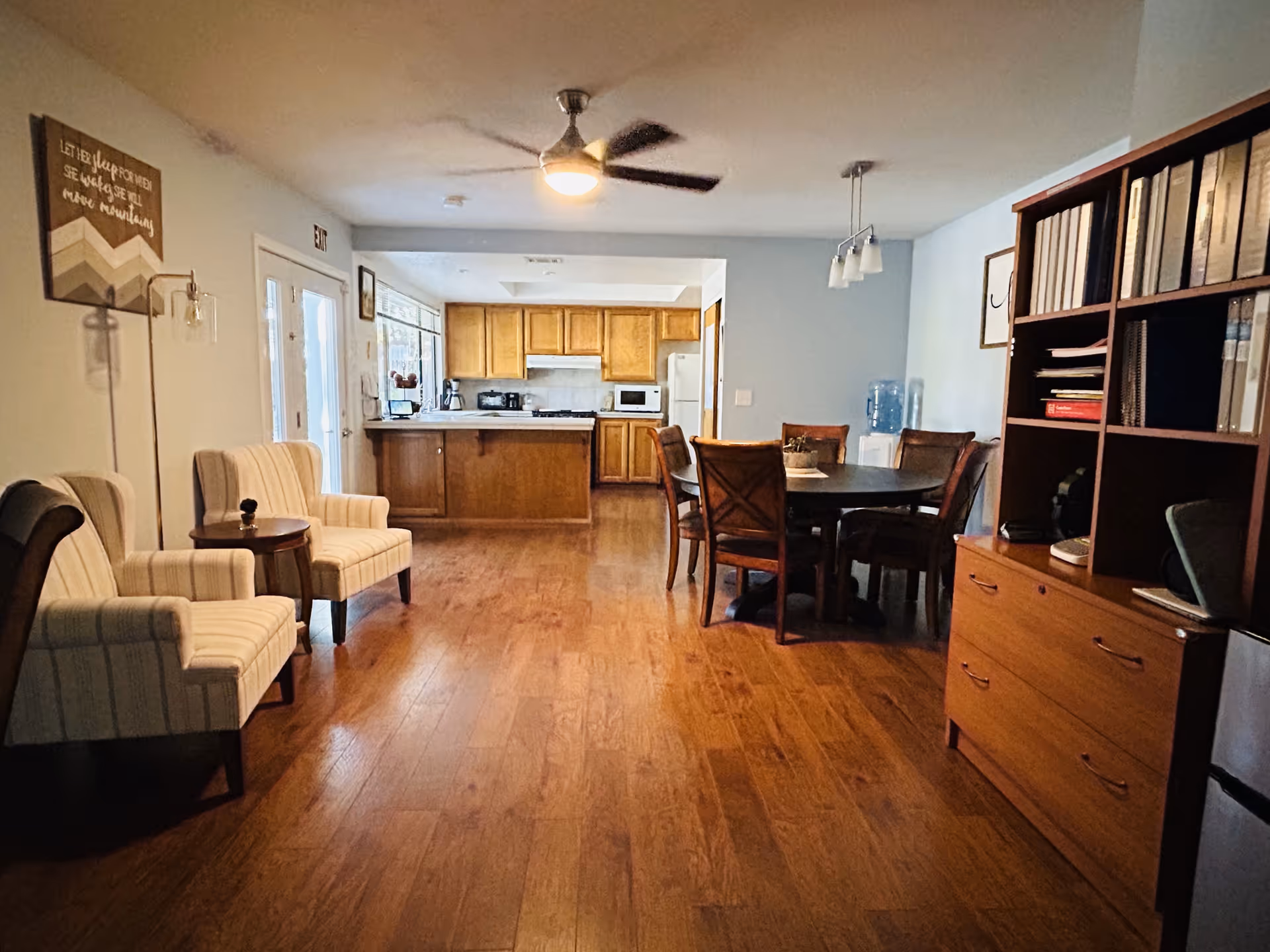A spacious common area with chairs, dining table, and a kitchen in back.