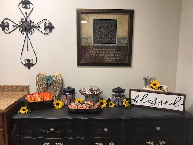 Dark sideboard with snacks, sunflowers, framed art, and decorative crosses on the wall.