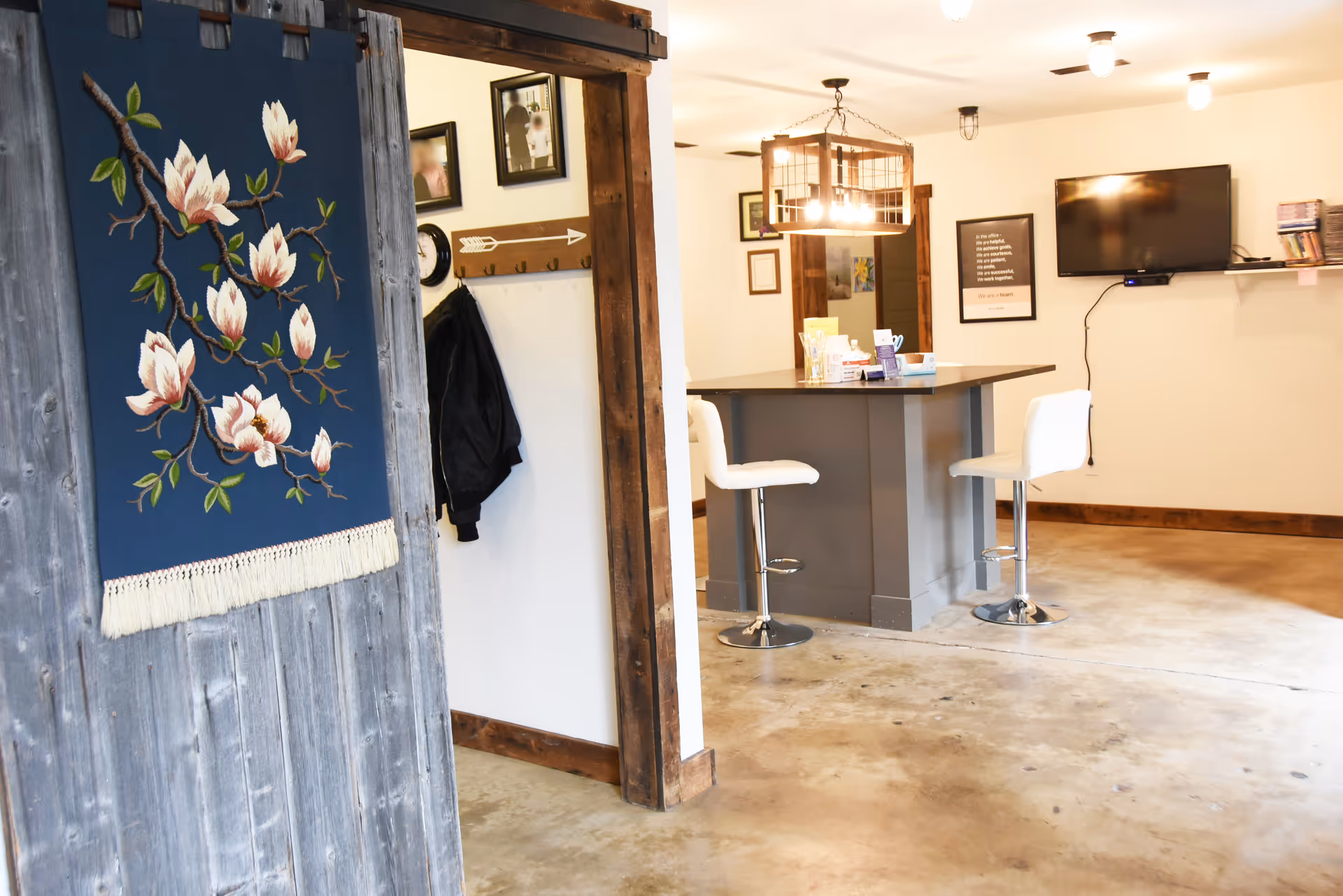 Cozy lobby area with a high counter, white stools, mounted TV, and rustic decor.