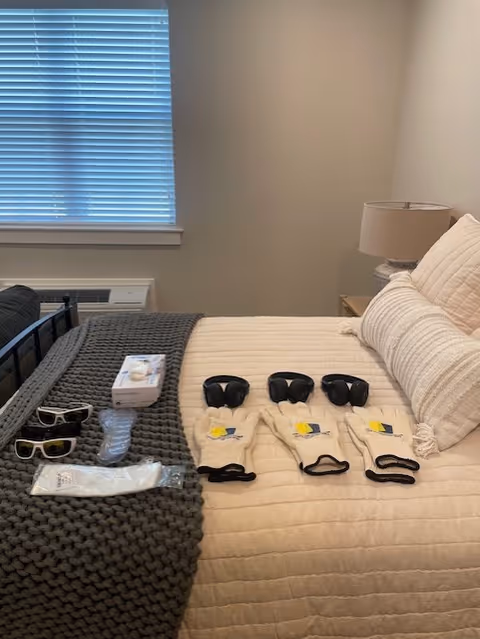 A neatly made bedroom in a Senior Helpers facility with a bed and items laid out.
