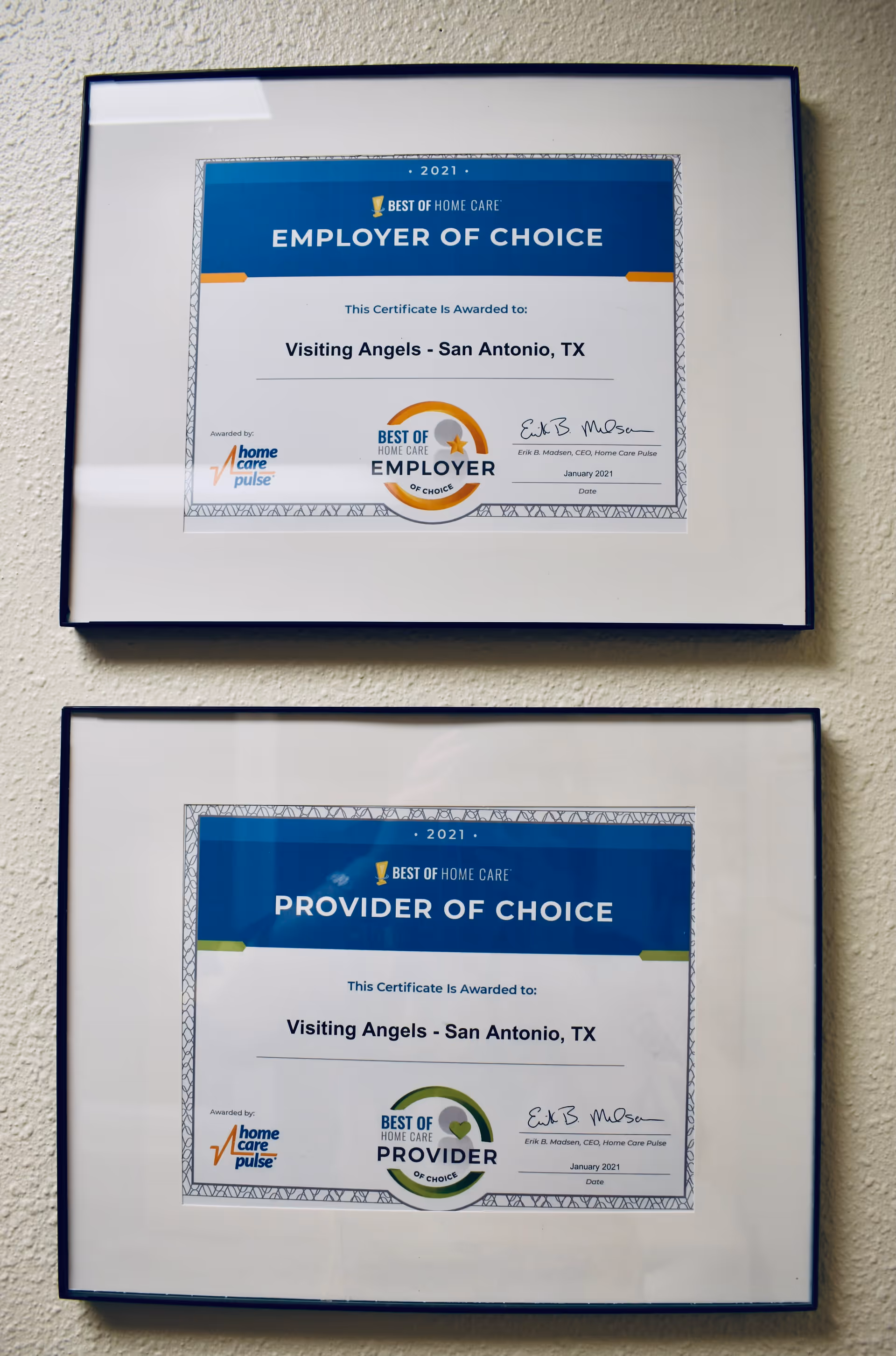 Two framed certificates mounted on a wall displaying award recognitions for Visiting Angels.