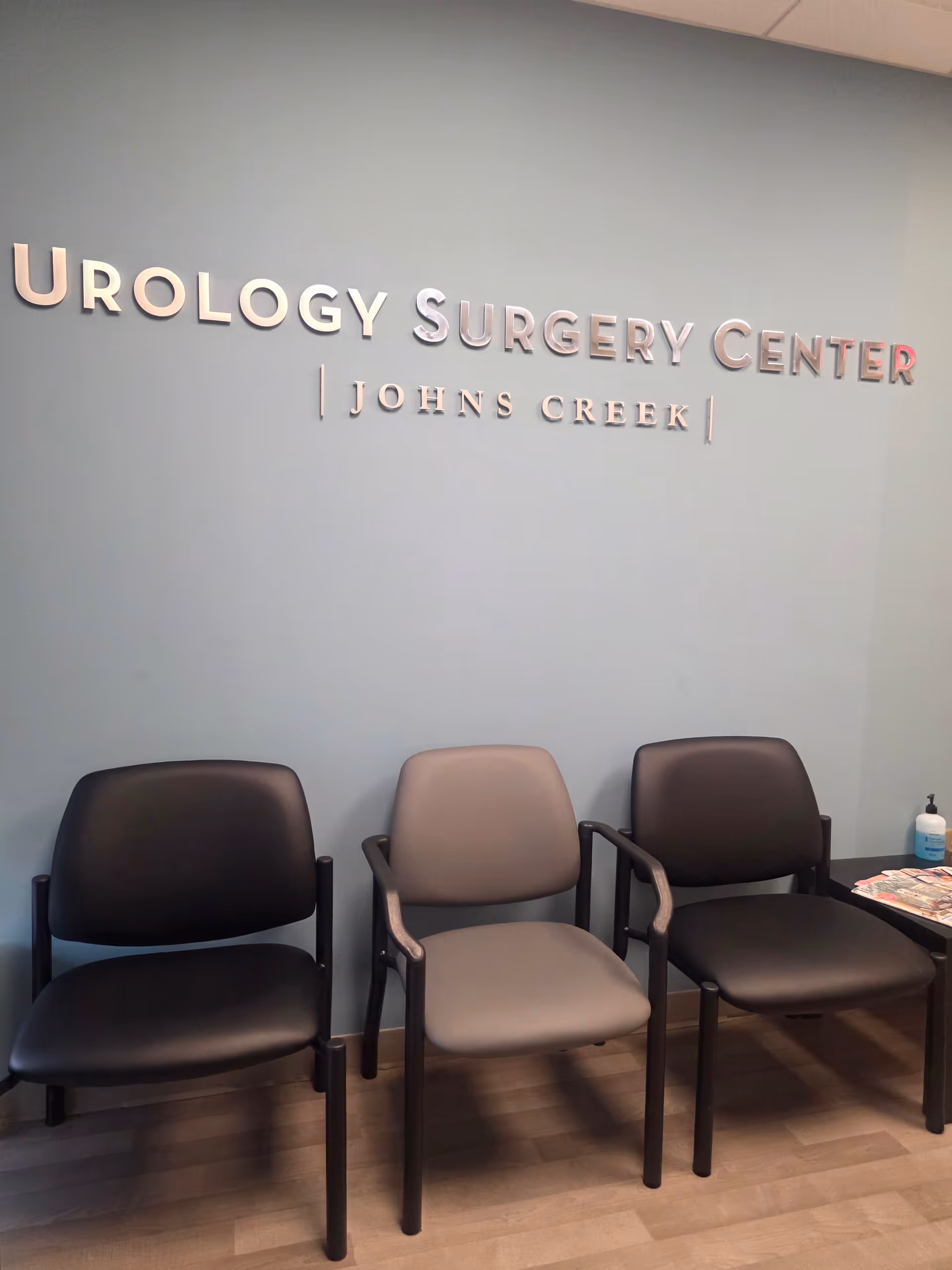 Waiting area with three chairs against a wall sign that says Urology Surgery Center.