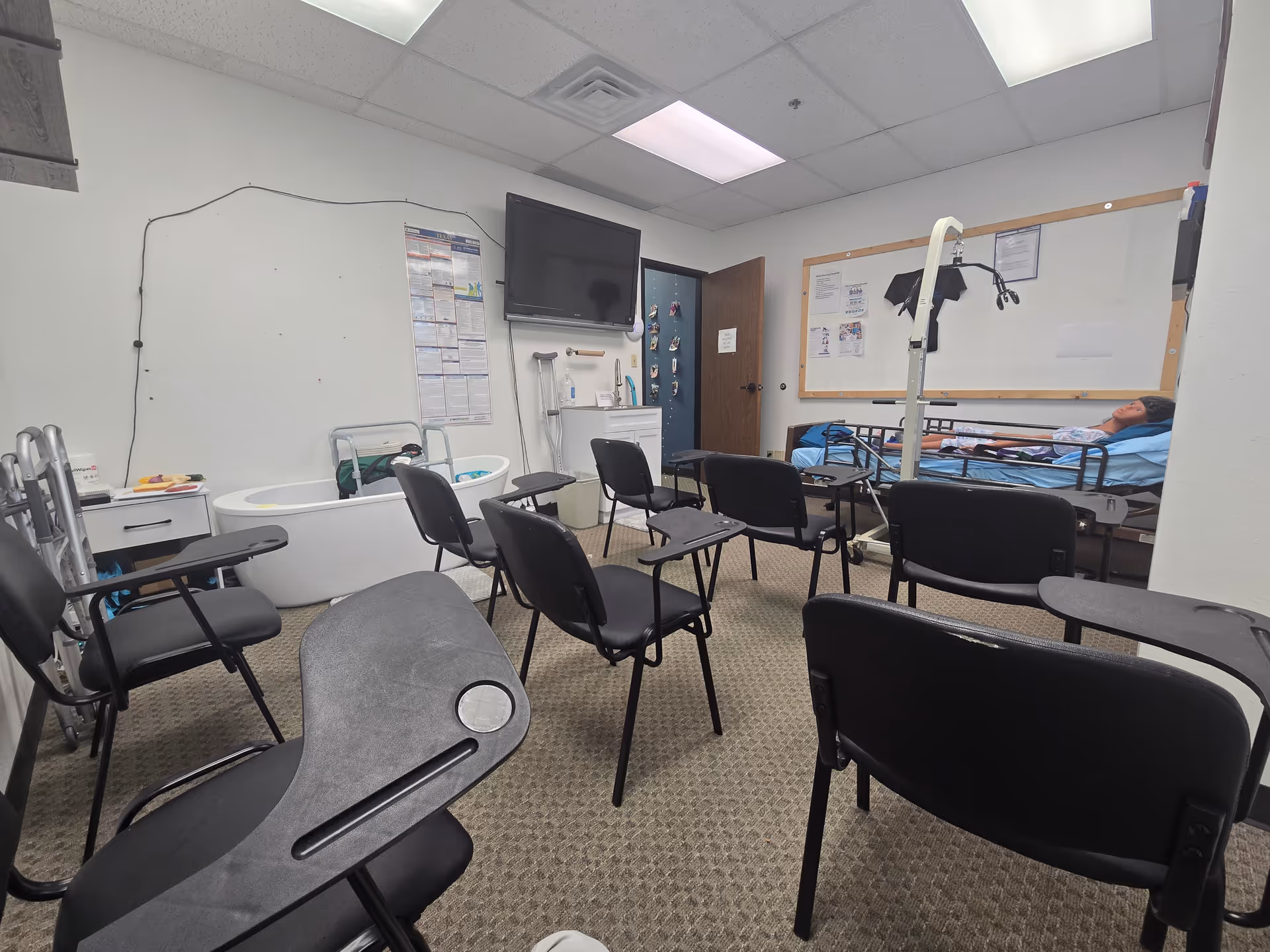 Treatment room in a senior home with patient on bed and rows of chairs.