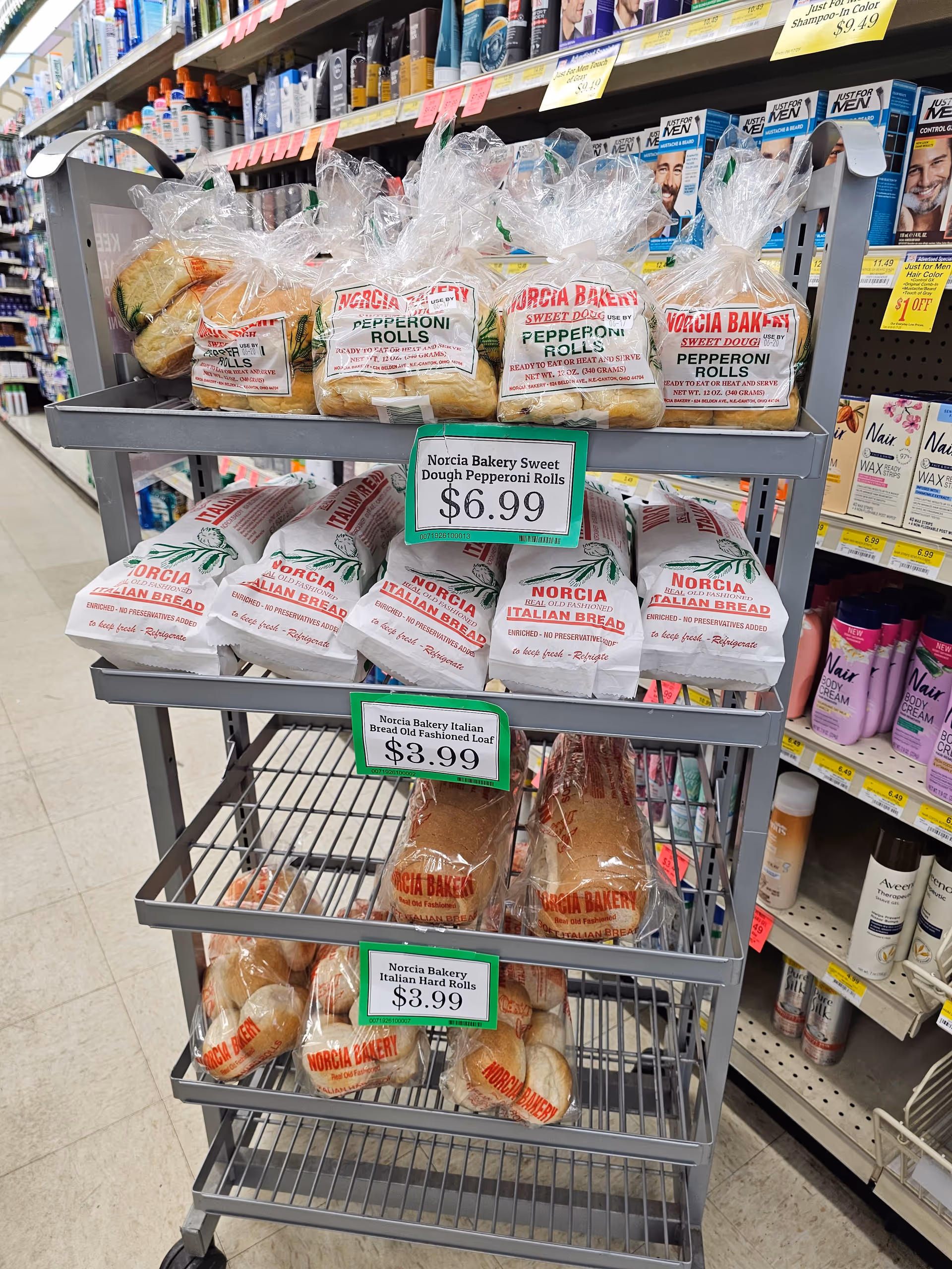 A wheeled display cart in a grocery store stocked with Norcia Bakery bread.