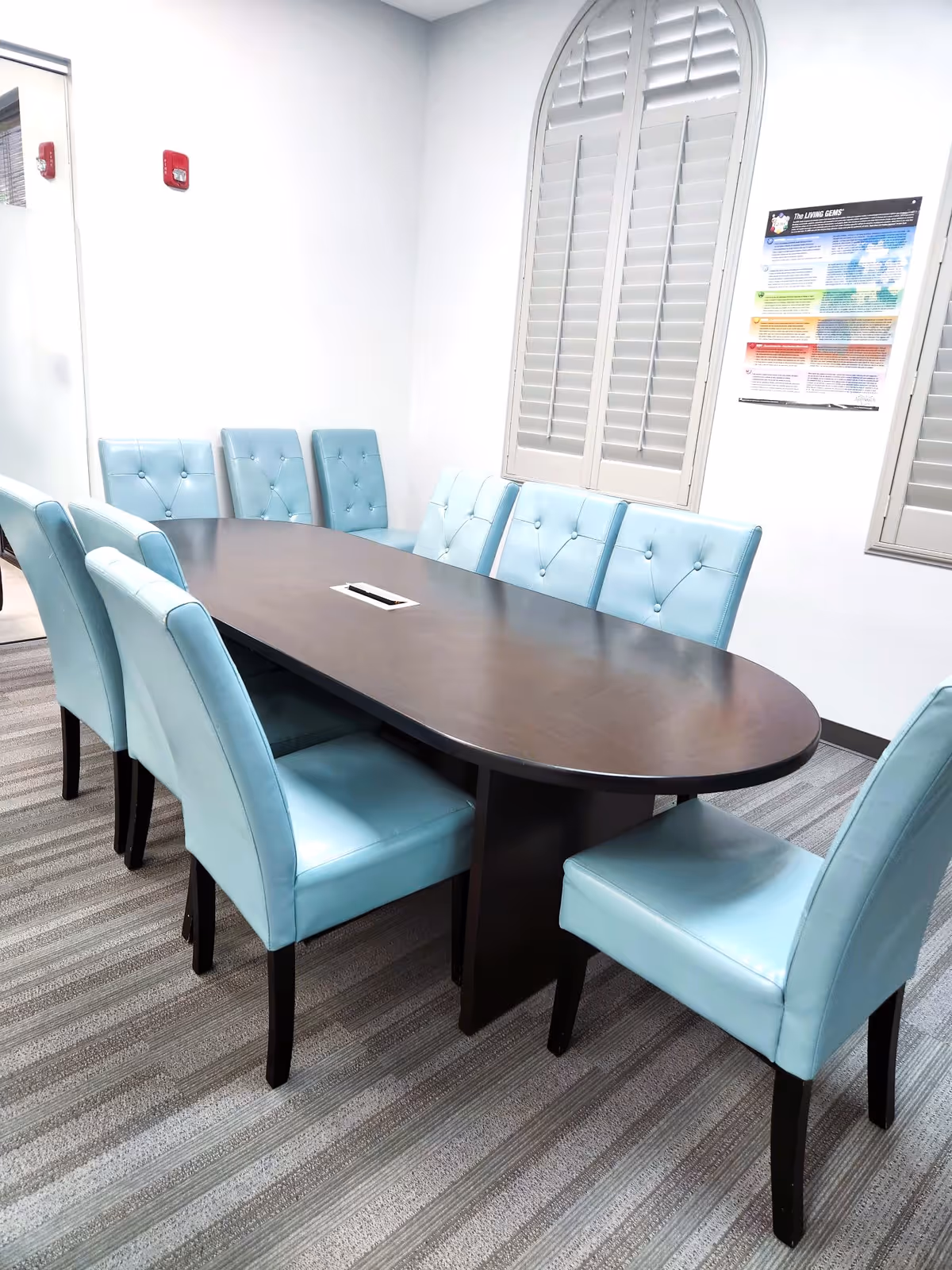 Conference room with a long dark table and blue upholstered chairs inside a Senior Helpers facility.