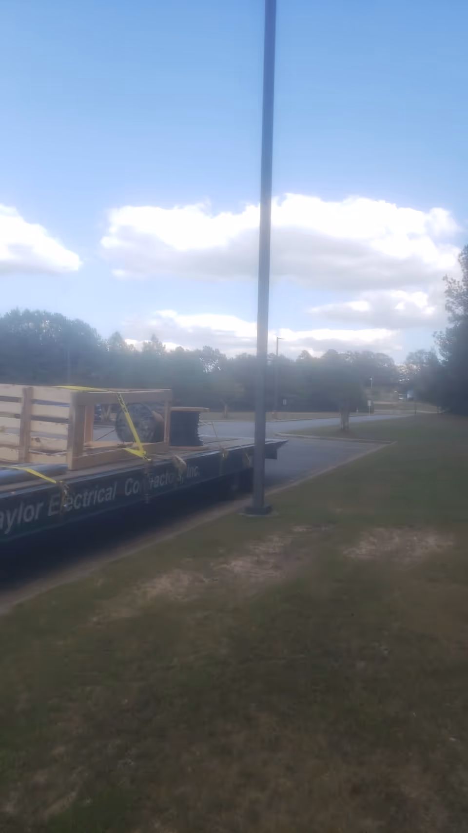 Outdoor scene with a flatbed trailer carrying wooden crates beside a grassy road.