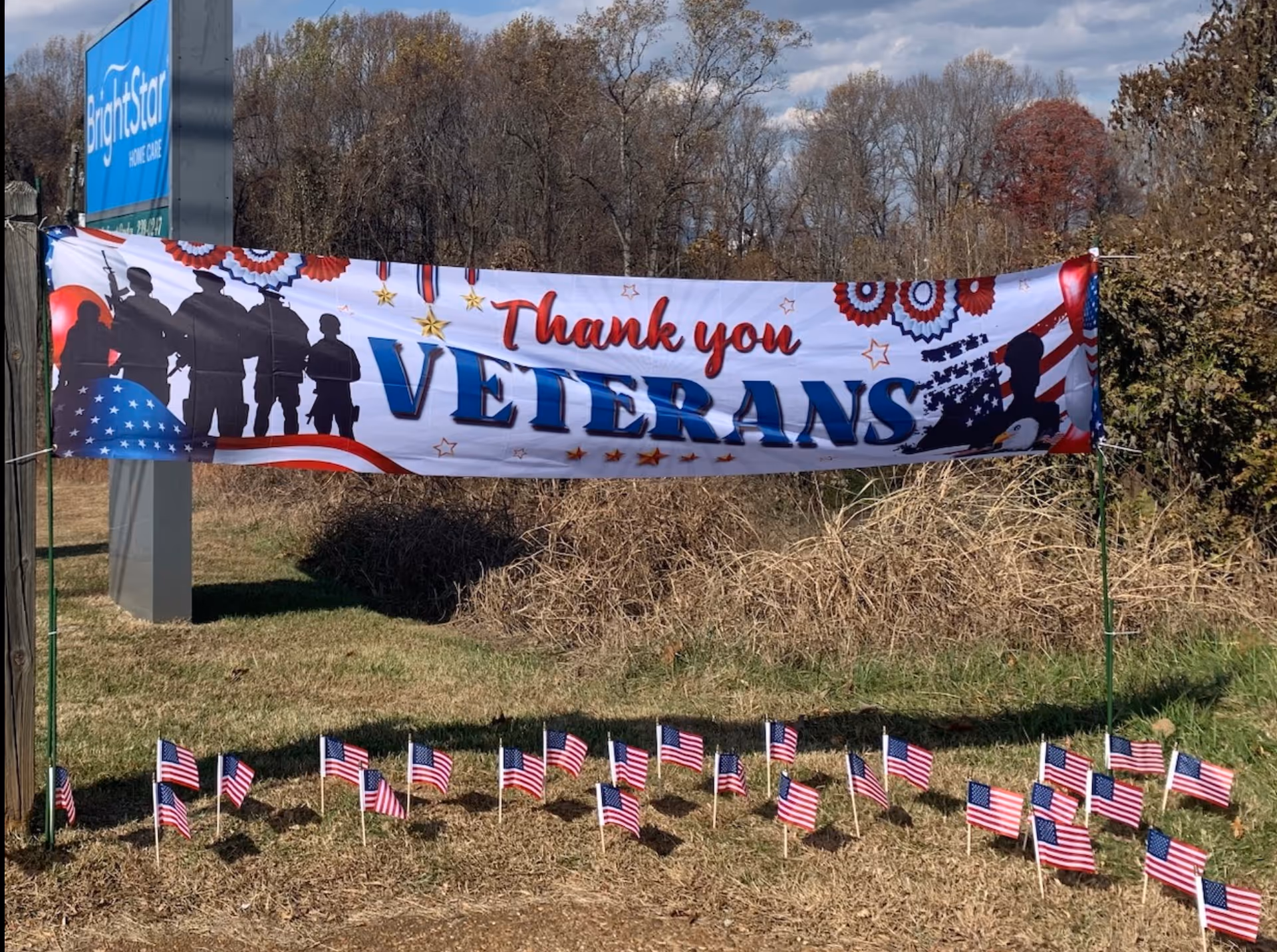 BrightStar Care outdoor display with a Thank you Veterans banner and small American flags on grass.