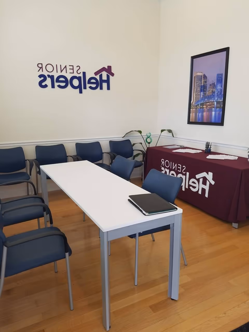 Interior conference room with blue chairs around a white table and Senior Helpers branding.
