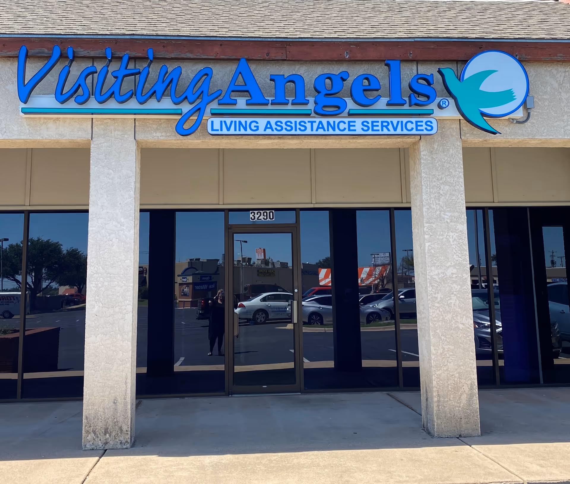 Exterior of Visiting Angels center with prominent blue sign and glass entrance.