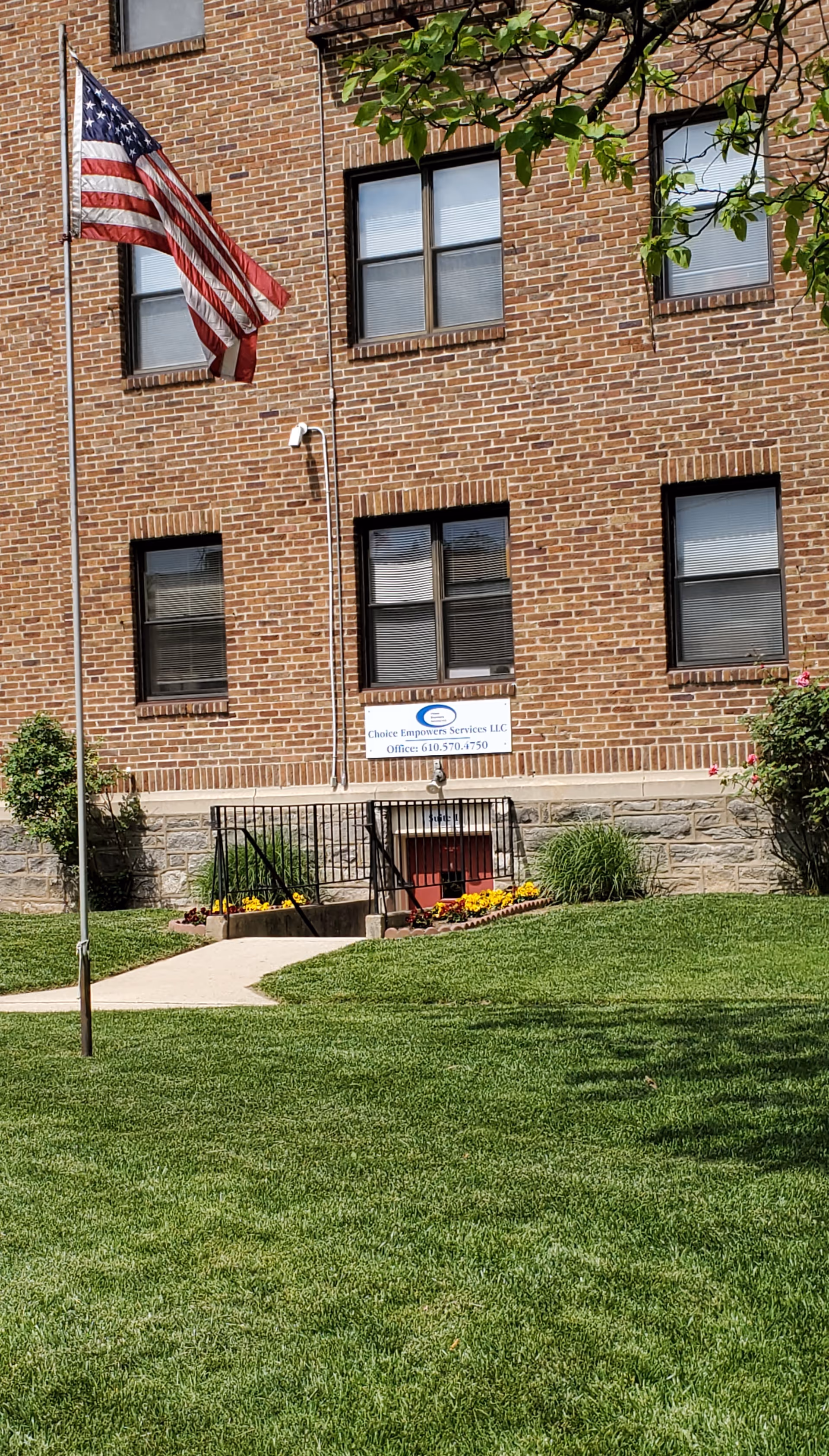 Brick building exterior with American flag, entrance steps, and a sign for Choice Empowers Services LLC.