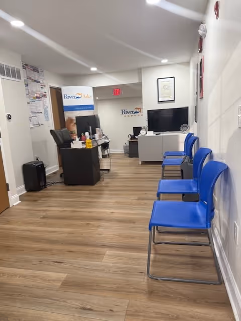 Long hallway inside River Oaks Home Care with blue chairs and a reception desk.